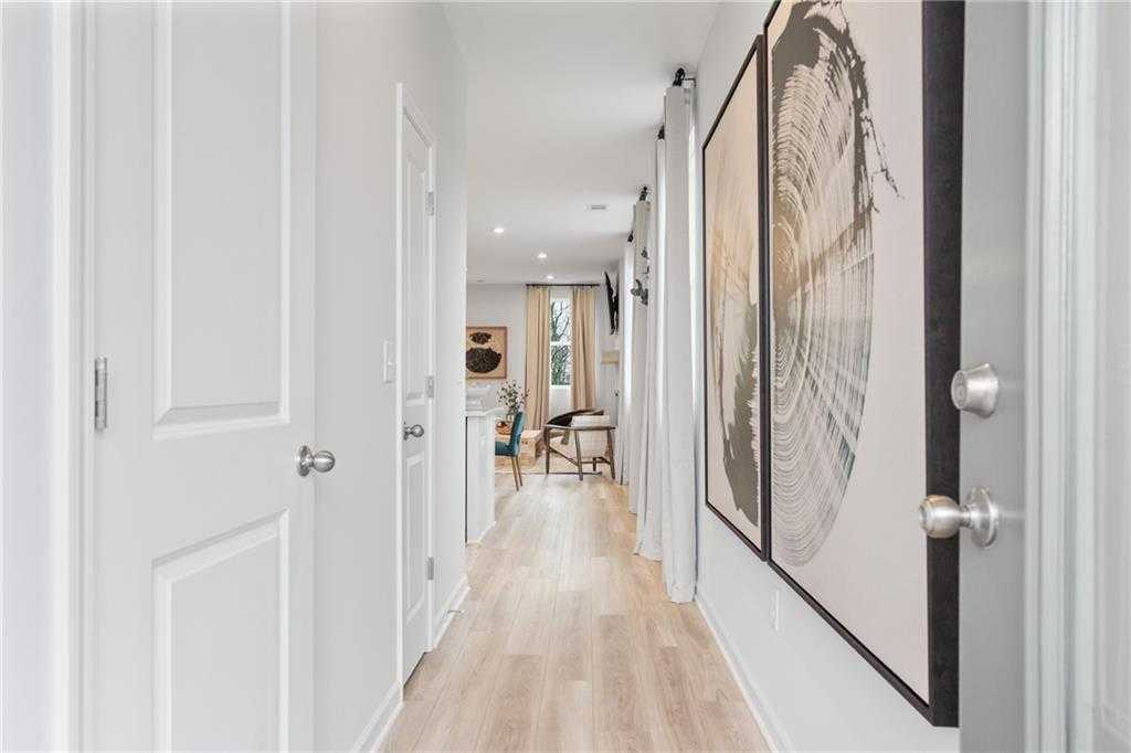 Elegant hallway with light oak floors, white doors, and large abstract wall art in Davidson Homes Wilmington B, Emerson, GA