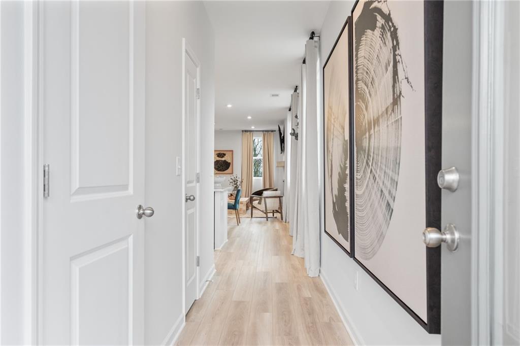 Elegant hallway with white doors, light oak floors, and large abstract wall art in Davidson Homes The Wilmington B, Emerson, GA