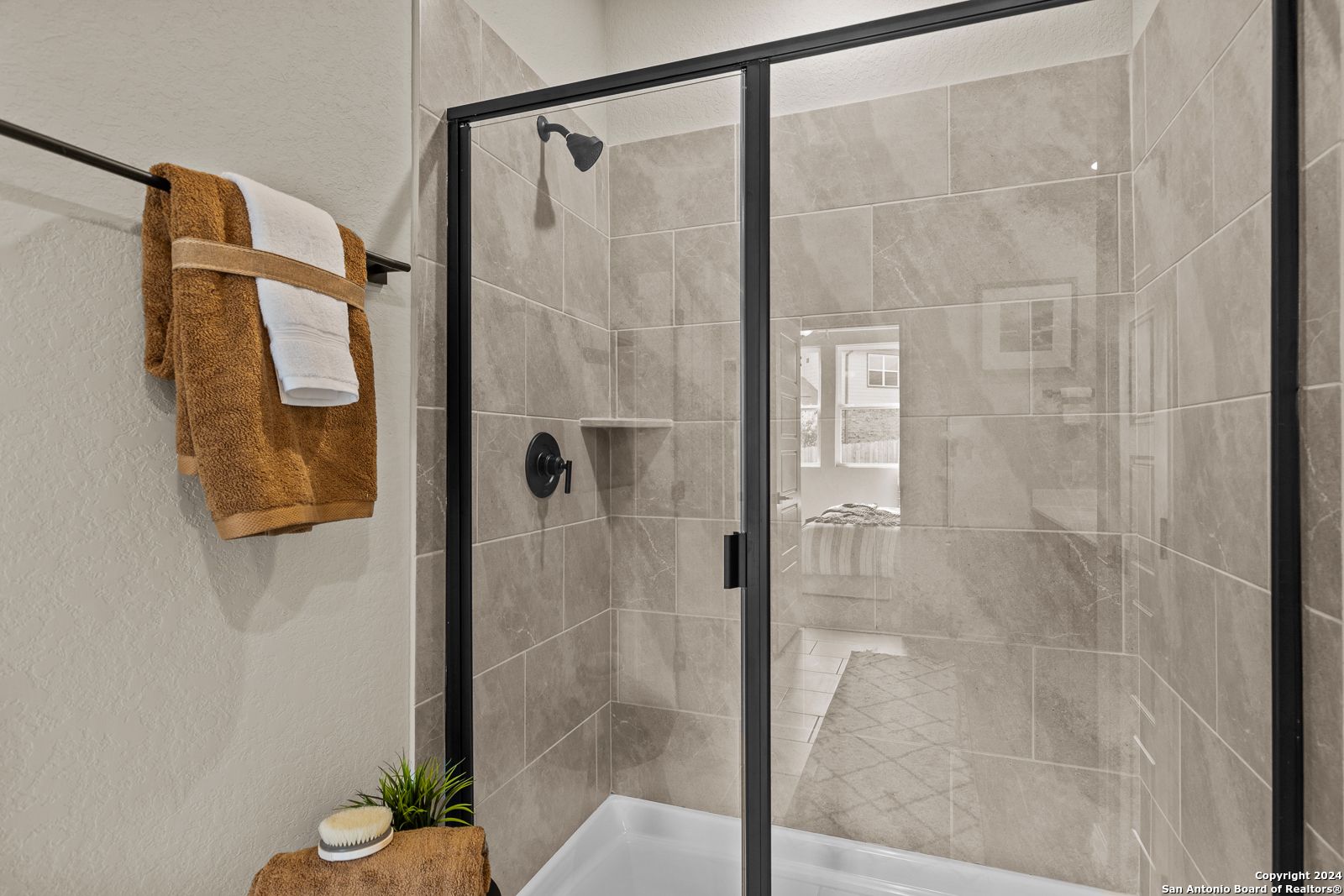 Modern frameless glass shower with beige subway tiles and black fixtures in Davidson Homes The Douglas F master bath, San Antonio