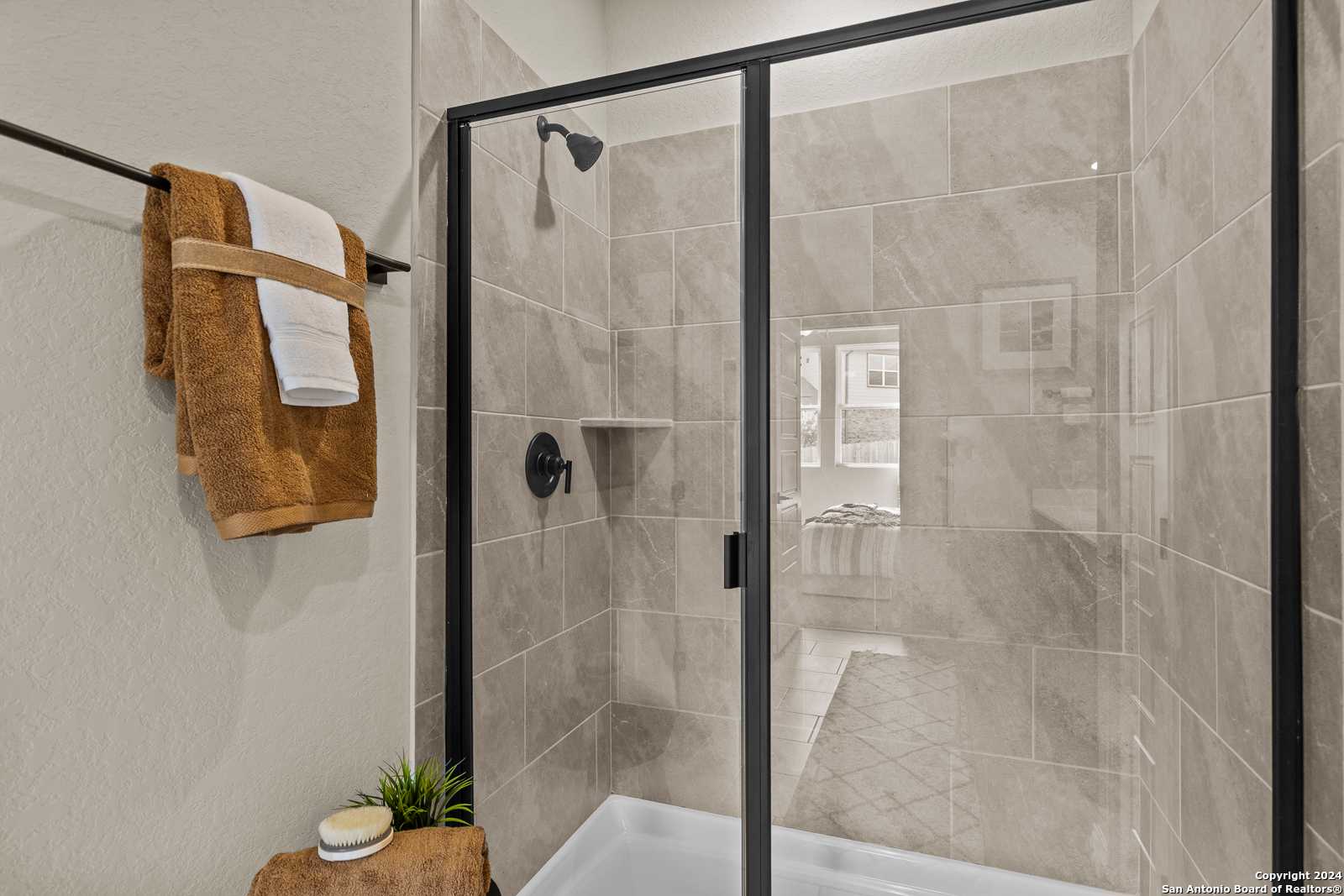 Modern frameless glass shower with beige subway tiles and black fixtures in Davidson Homes The Douglas F master bath, San Antonio
