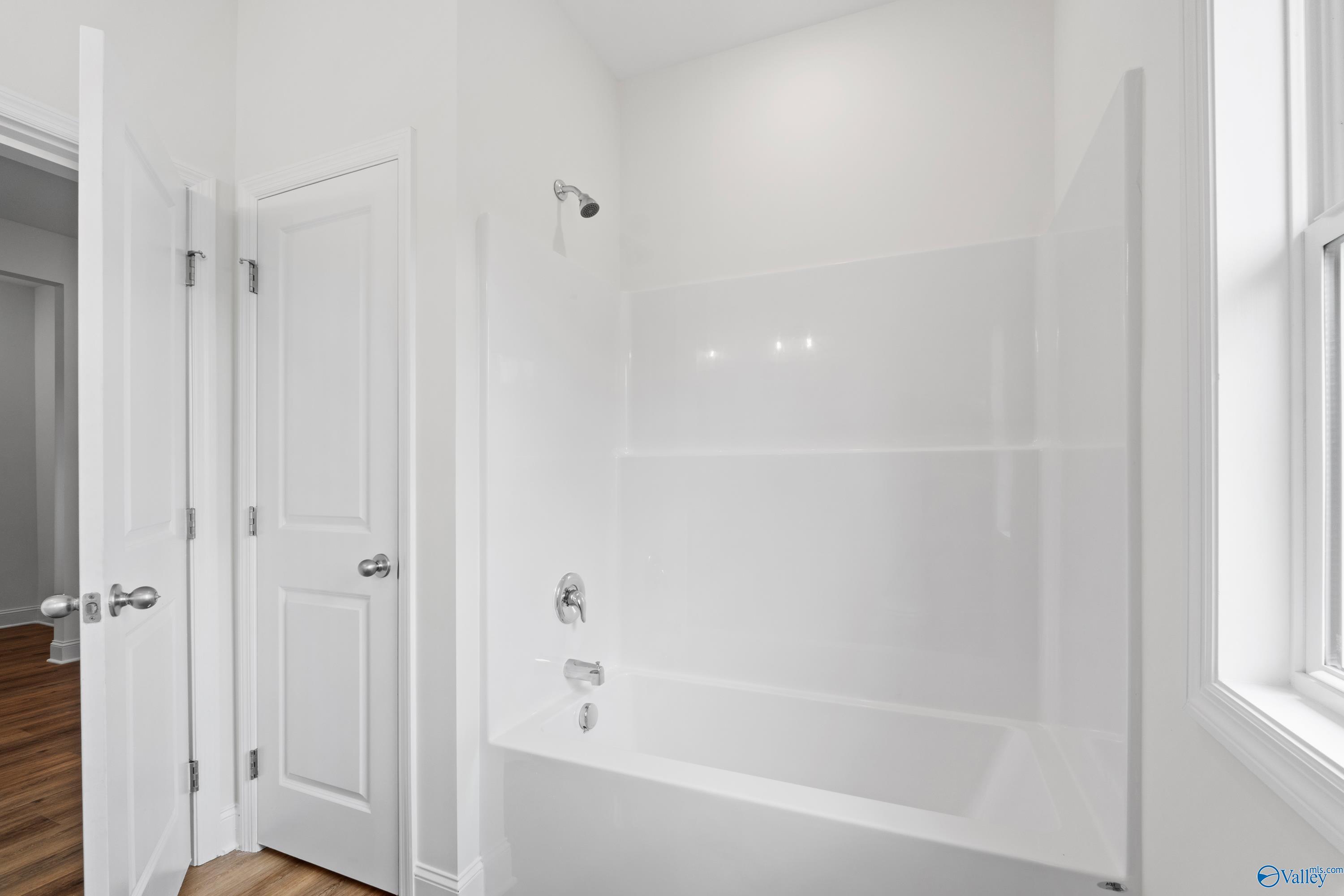 Modern white bathroom with tub and shower combo in The Everett B floor plan by Davidson Homes in Athens, Alabama.