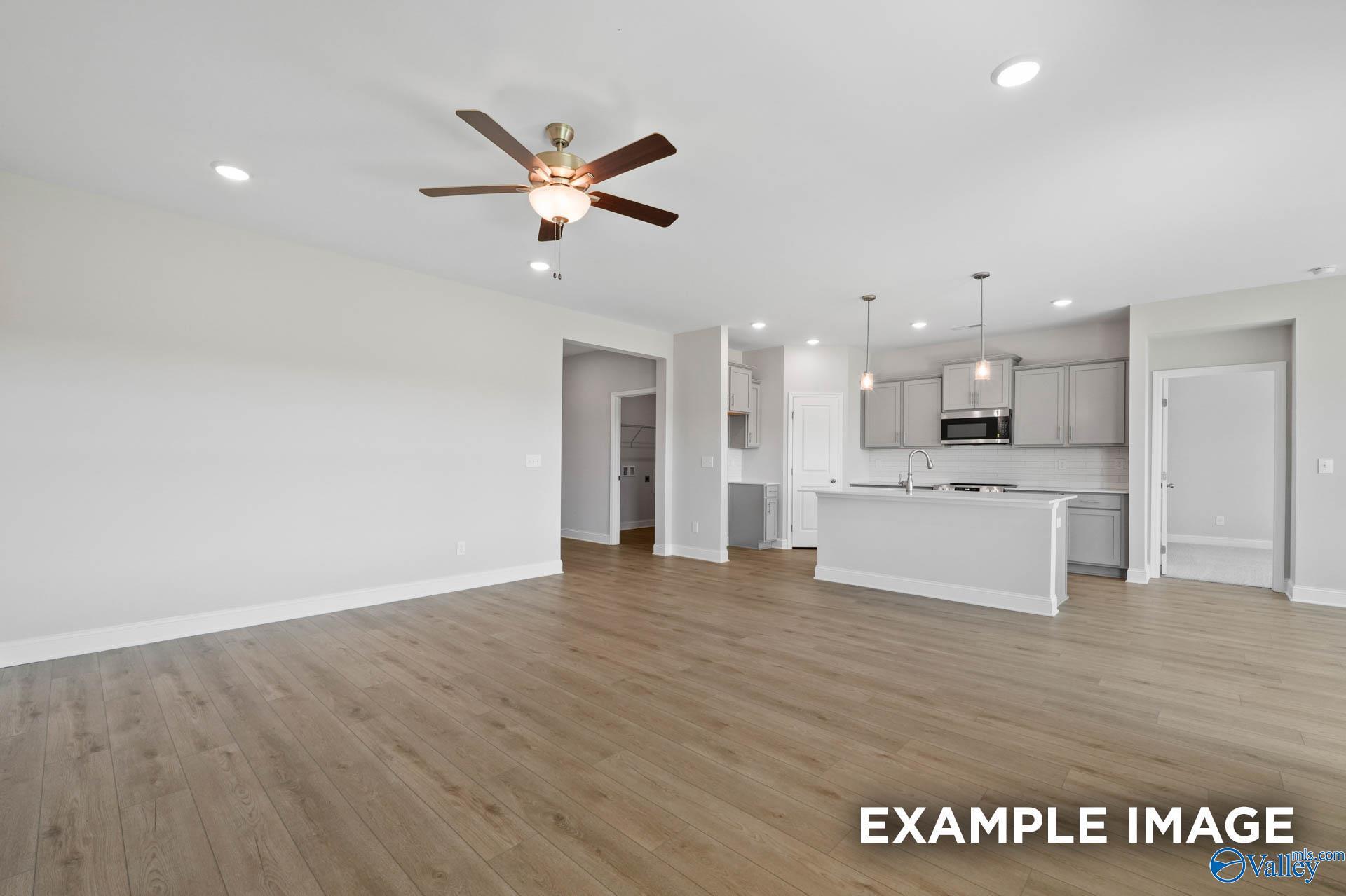 Open-concept living room and kitchen with grey cabinetry in The Everett B floor plan at The Meadows, Athens, Alabama.