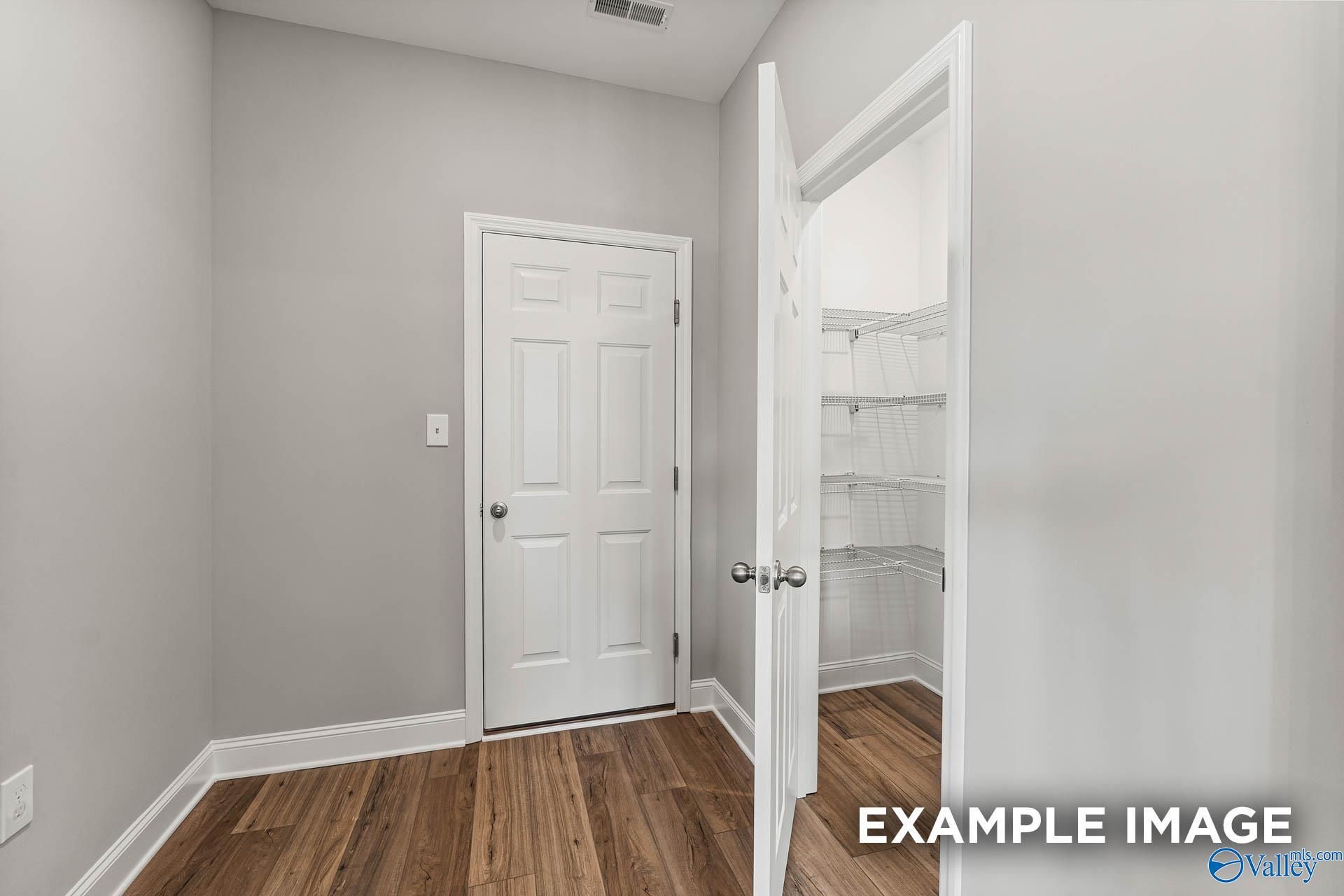 Bright bedroom with open walk-in closet shelving and hardwood floors in Davidson Homes The Chelsea A, Athens, Alabama