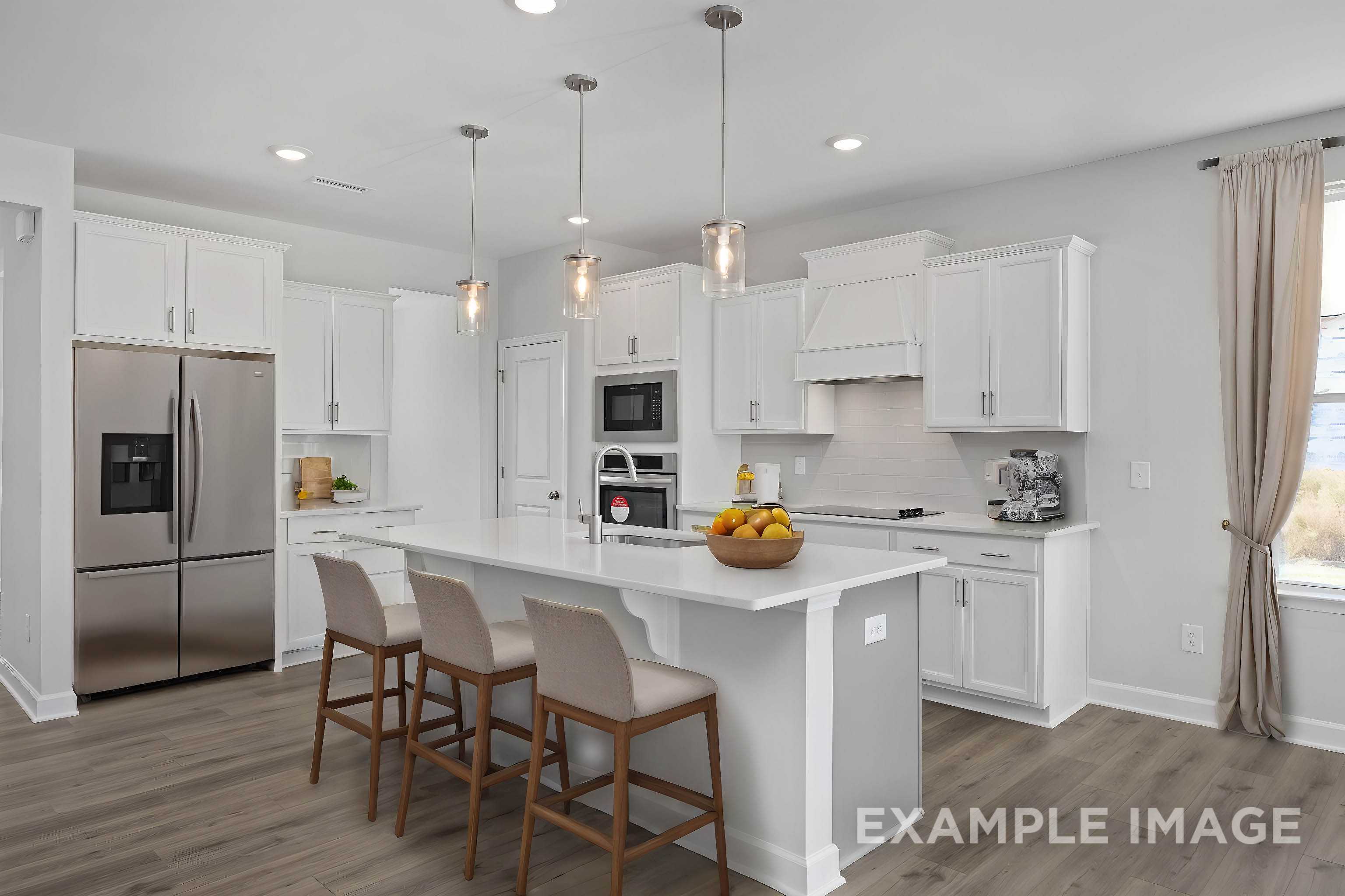 Spacious gourmet kitchen in The Ash C with white shaker cabinets, large center island, pendant lights, and stainless steel appliances