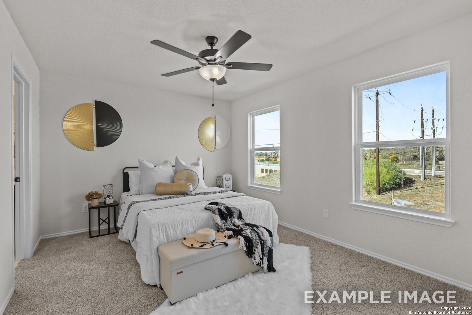 Serene bedroom with king bed, ceiling fan, gold wall art, and scenic window views in Davidson Homes Trinity B, San Antonio