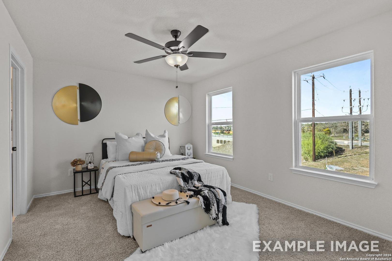 Serene bedroom with king bed, ceiling fan, gold wall art, and scenic window views in Davidson Homes Trinity B, San Antonio