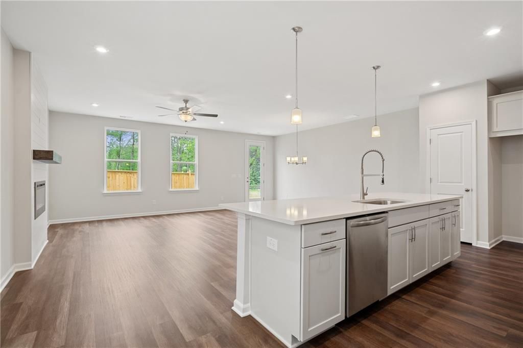 Open-concept kitchen with white island, stainless dishwasher, pendant lights, and hardwood floors in Davidson Homes Cary B, Kennesaw, GA