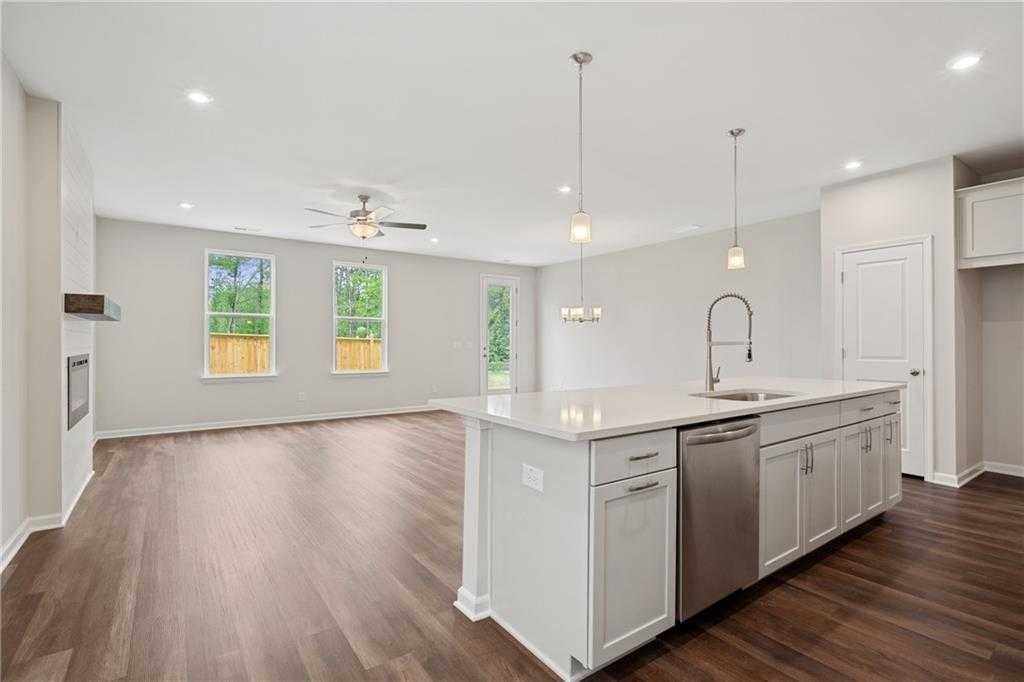 Open-concept kitchen with white island, stainless dishwasher, pendant lights, and hardwood floors in Davidson Homes Cary B, Kennesaw, GA
