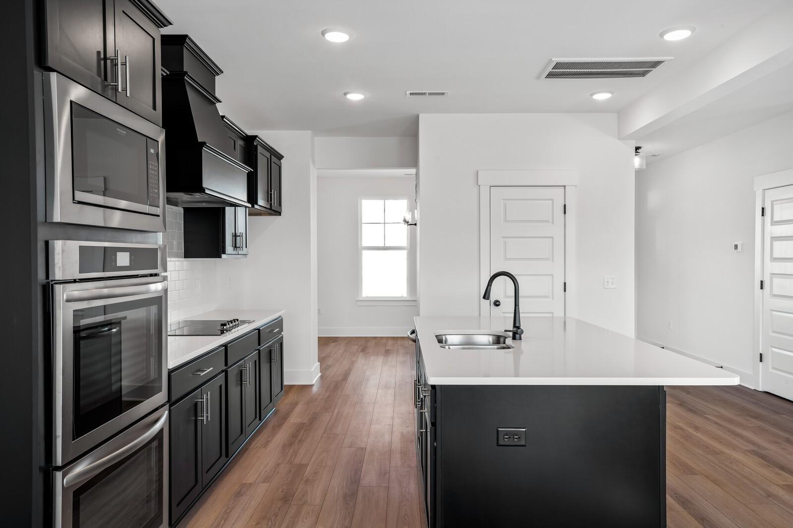 Modern kitchen with black shaker cabinets, white quartz island, stainless steel appliances in Davidson Homes The Willow, Gallatin, TN
