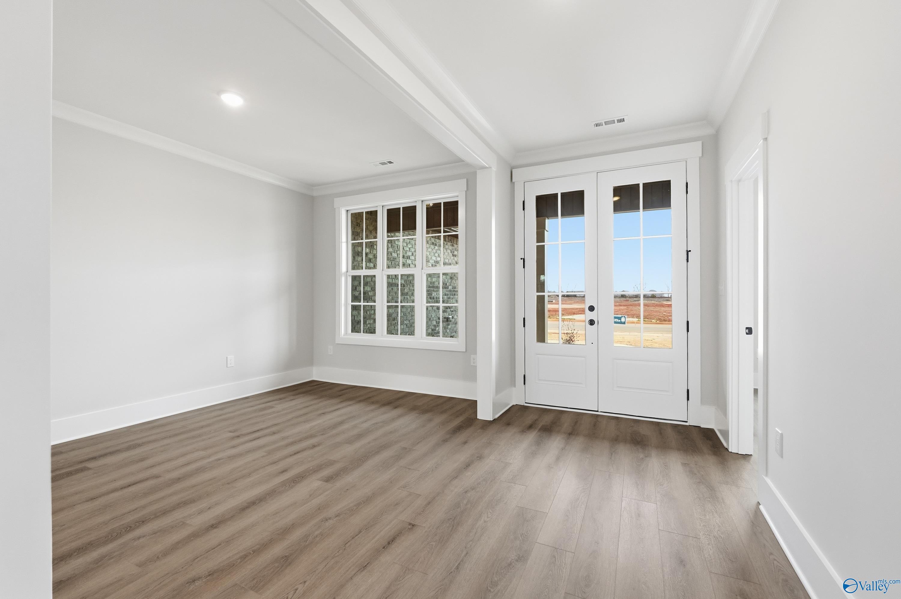 Bright living room with hardwood floors, French doors to backyard, and large windows in Davidson Homes The Finleigh, Meridianville, AL