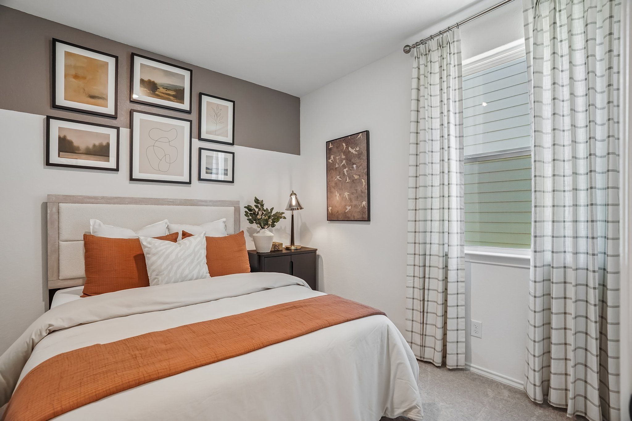 Cozy bedroom with terracotta accents and gallery wall at Fairway Crossing in Converse, TX by Davidson Homes.