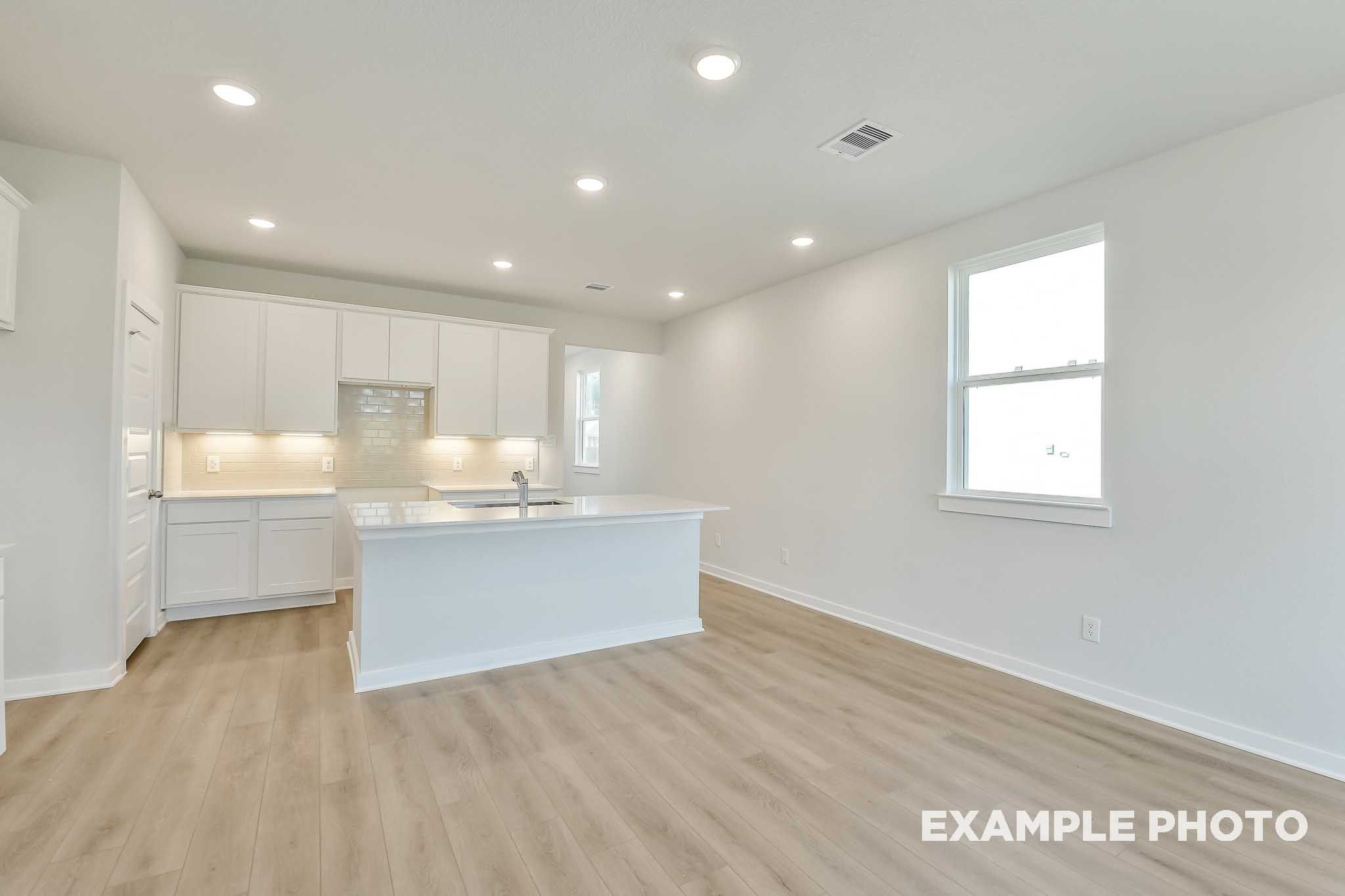 Bright open-concept kitchen and living area in The Colorado by Davidson Homes, featuring white cabinetry and island