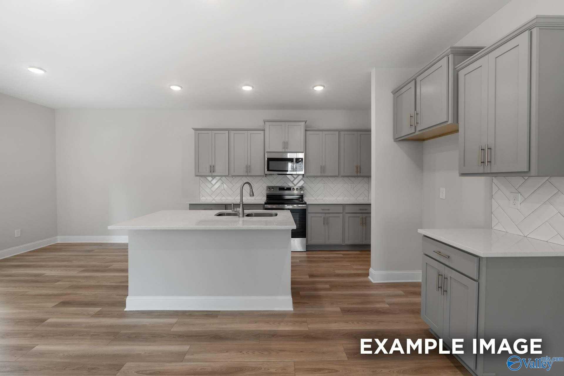 Modern kitchen with gray shaker cabinets, white island, stainless appliances, subway tile backsplash in The Camden by Davidson Homes, Huntsville AL