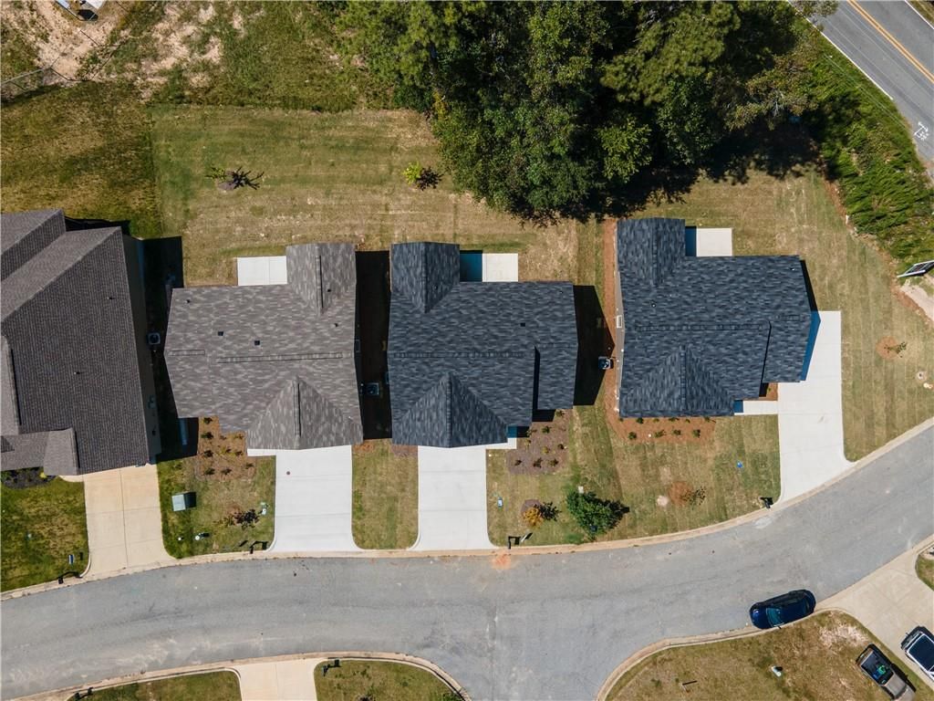 Aerial view of three modern single-story Davidson Homes with dark shingle roofs, garages, and landscaped yards in Summer Vineyard, Phenix City, Alabama
