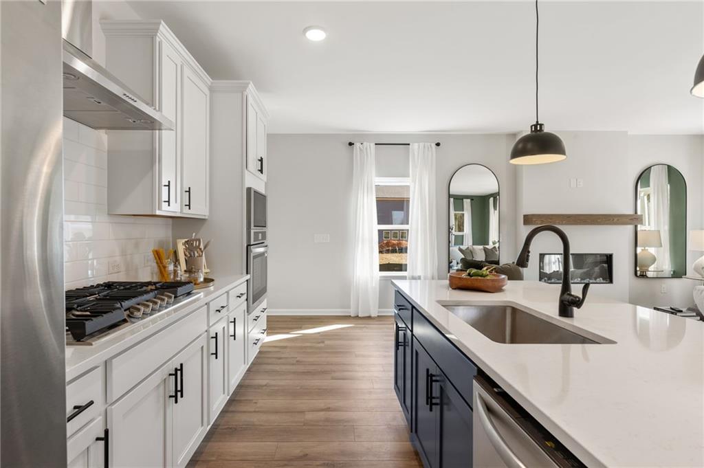 Modern kitchen with white cabinets, navy island, and stainless appliances in The Rabun B floor plan at The Bluffs, Canton.