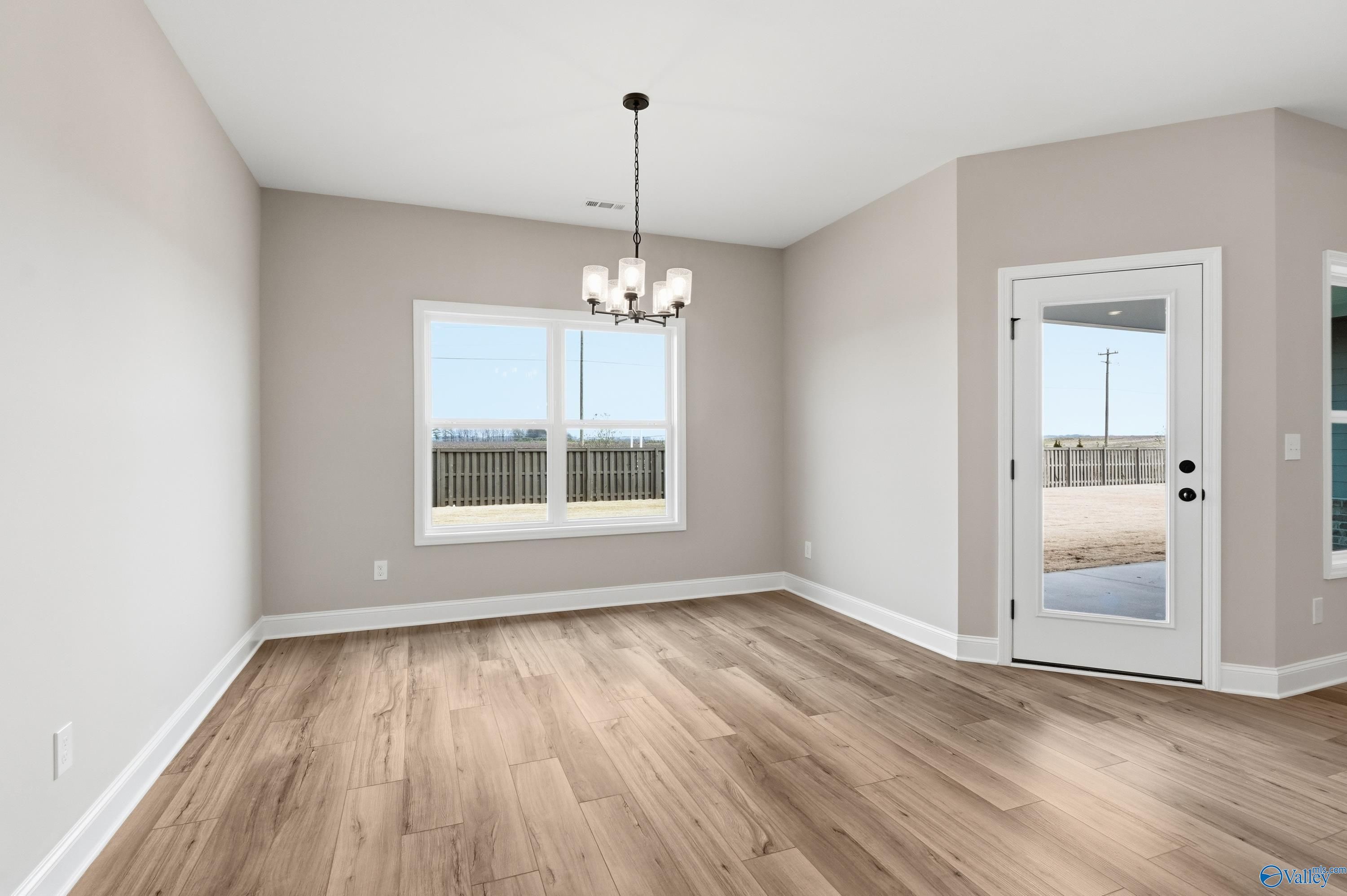 Bright dining room with hardwood floors, modern chandelier, large window and glass door in Davidson Homes The Rockford C, Athens AL