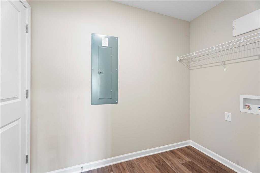 Utility laundry room with blue electrical panel, wire shelving, white sink, and beige walls in Davidson Homes The Washington, Phenix City, Alabama