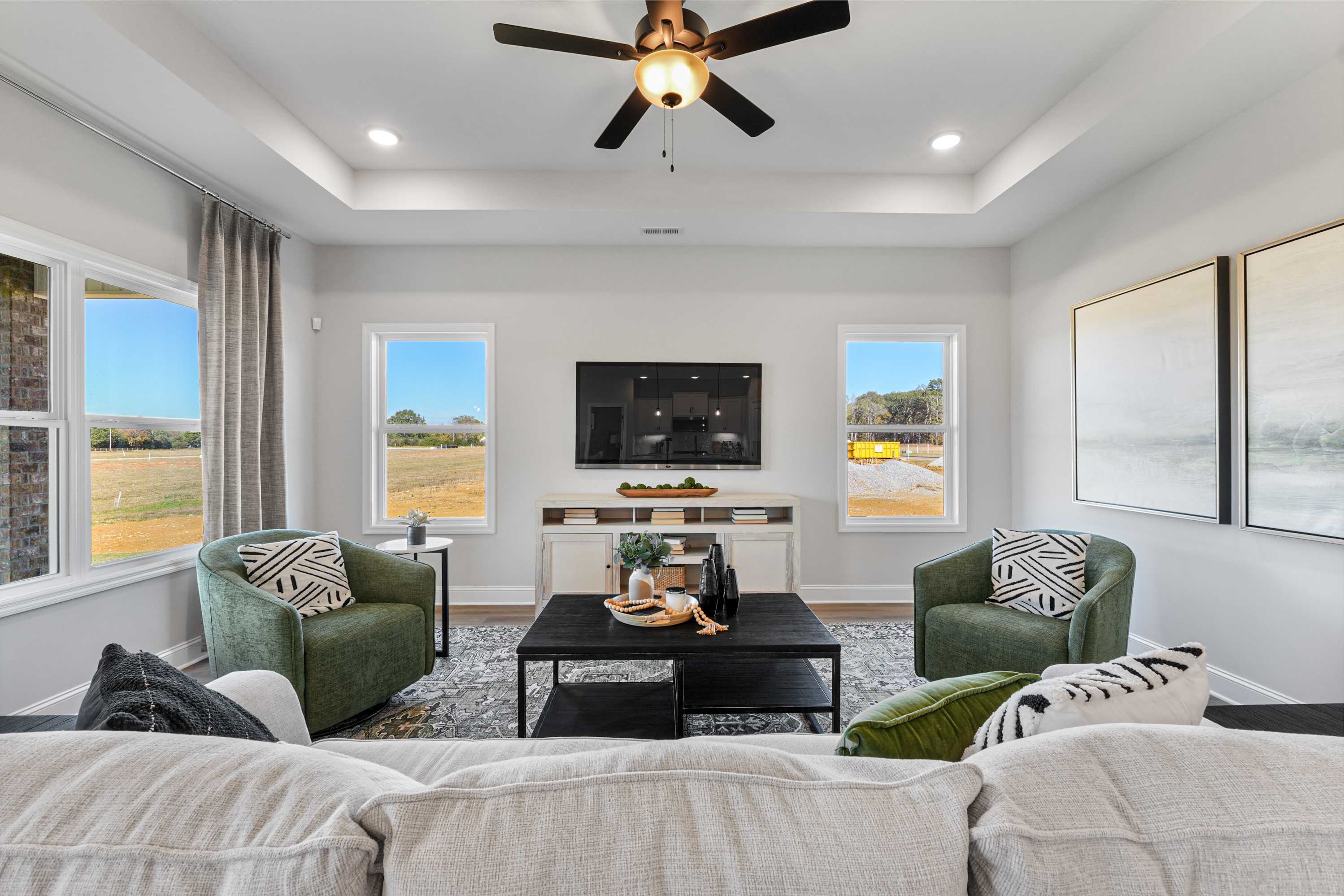 Spacious living room in Ramsay Cove, Owens Cross Roads AL featuring gray sectional sofa, patterned green armchairs, wall TV, and field views