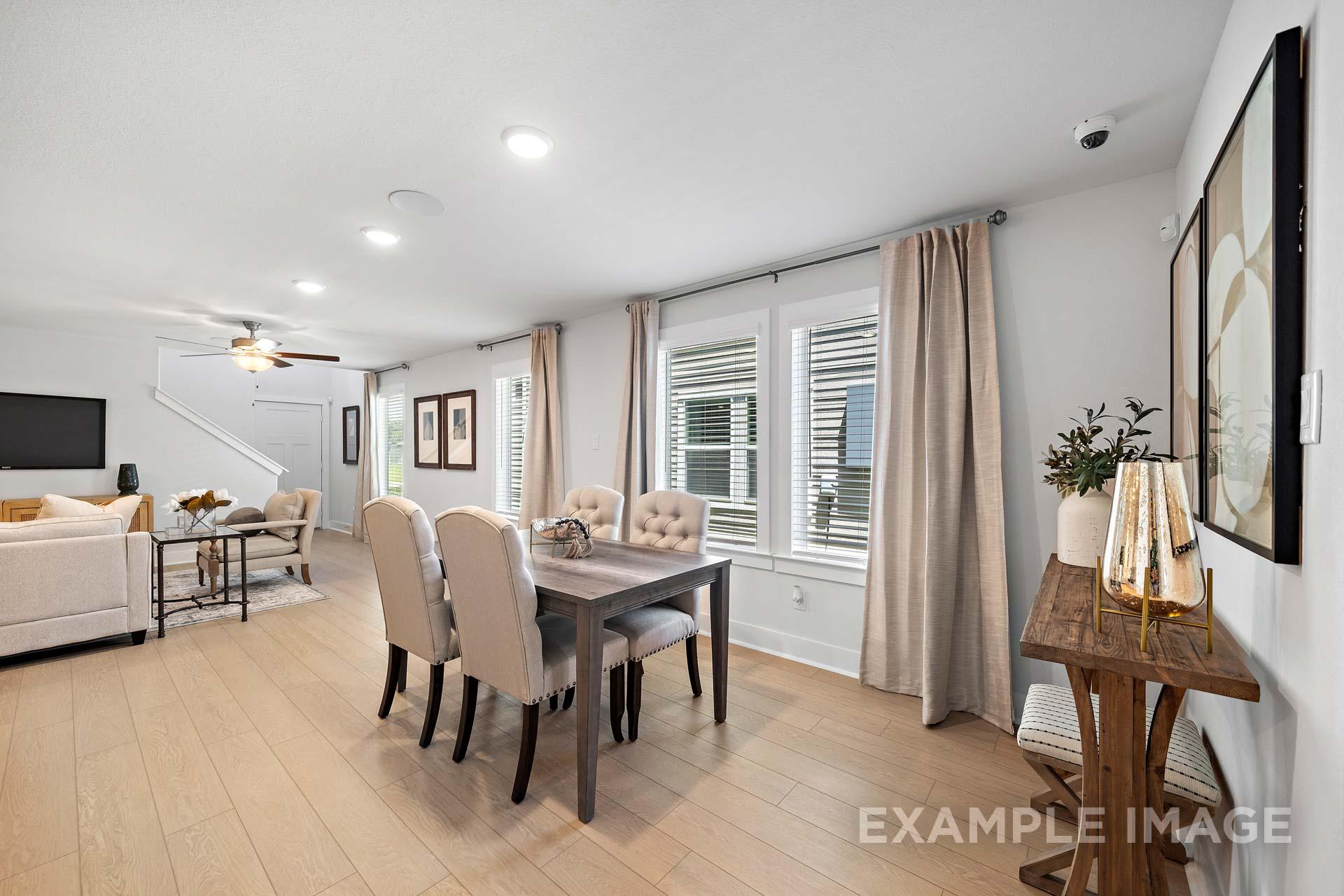 Open-concept living and dining area in The Rose B home with beige sofa, wood dining table, large windows, Cypress Texas design