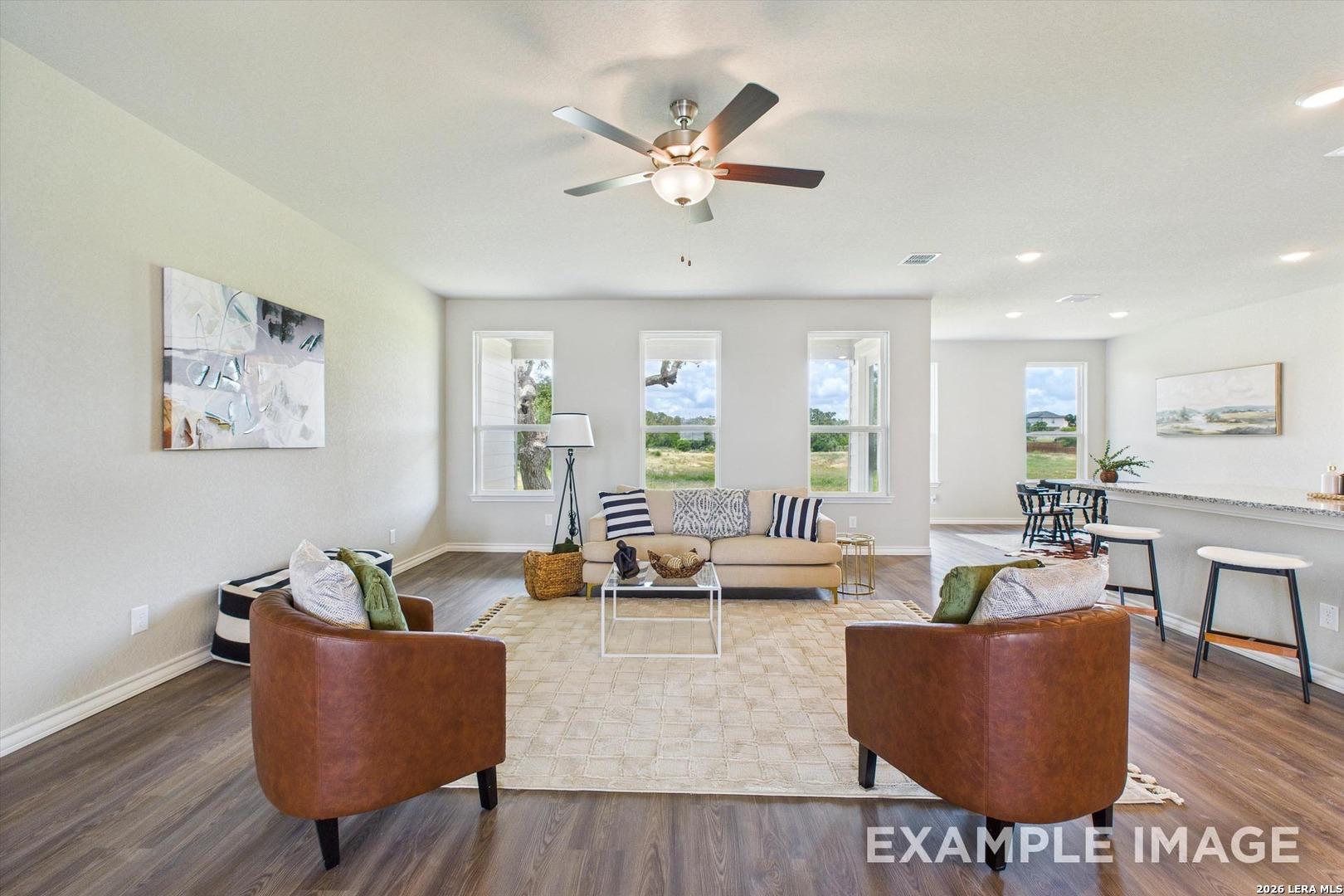 Open-concept living room with leather chairs and modern decor in The Foster F floor plan, Potranco Oaks, Castroville, TX.