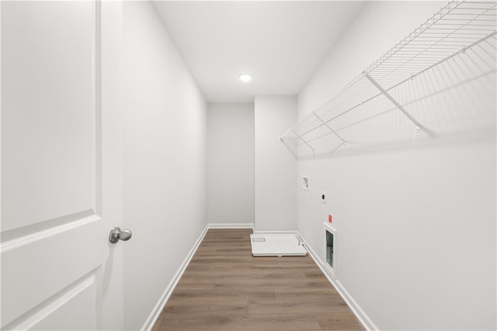 Laundry room with wire shelving and wood-style flooring in The Sinclair B floor plan at Cedar Farms, Winder, Georgia.