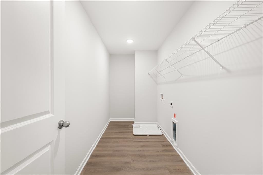 Laundry room with wire shelving and wood-style flooring in The Sinclair B floor plan at Cedar Farms, Winder, Georgia.