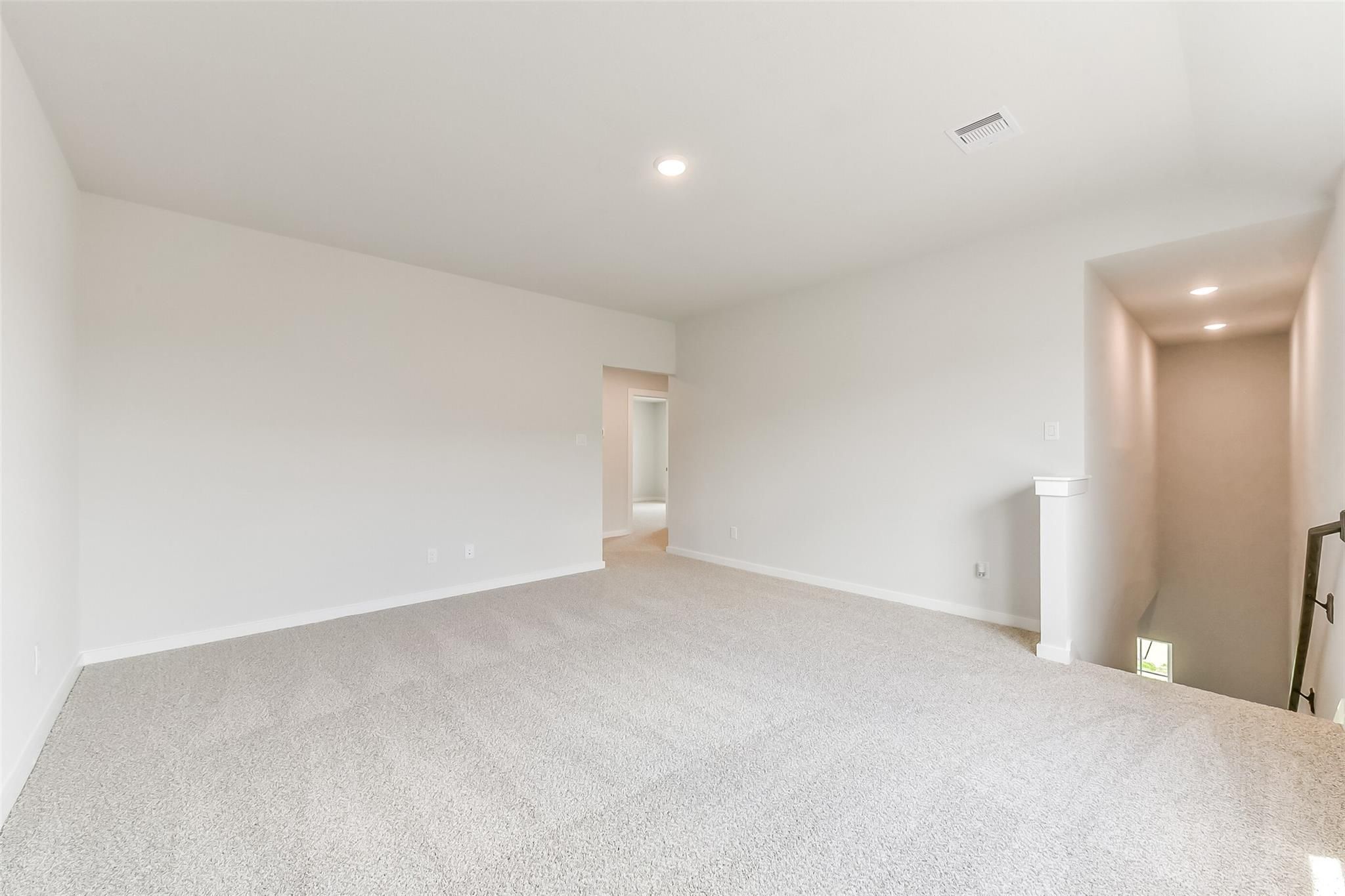 Spacious upstairs loft with beige carpet, white walls, recessed lighting, and staircase in 4-bedroom Davidson Homes The Tierra C, Dayton Texas