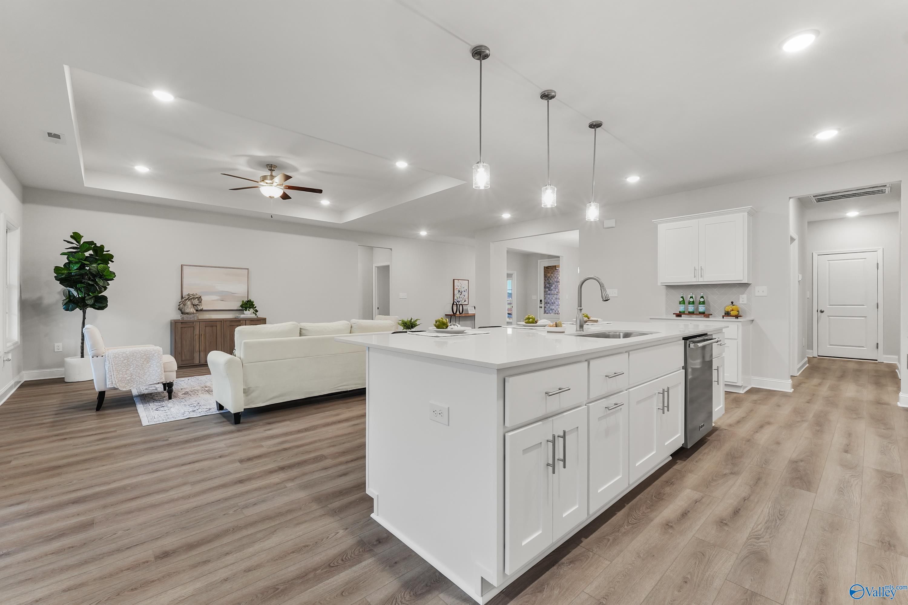 Modern open-concept kitchen-living room with white island, pendant lights, sectional sofa in Davidson Homes Finleigh, Toney Alabama
