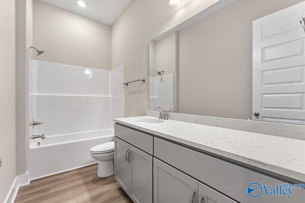 Modern bathroom with white quartz vanity, gray cabinets, bathtub shower combo in Evermore Homes The Oxford, Owens Cross Roads, AL