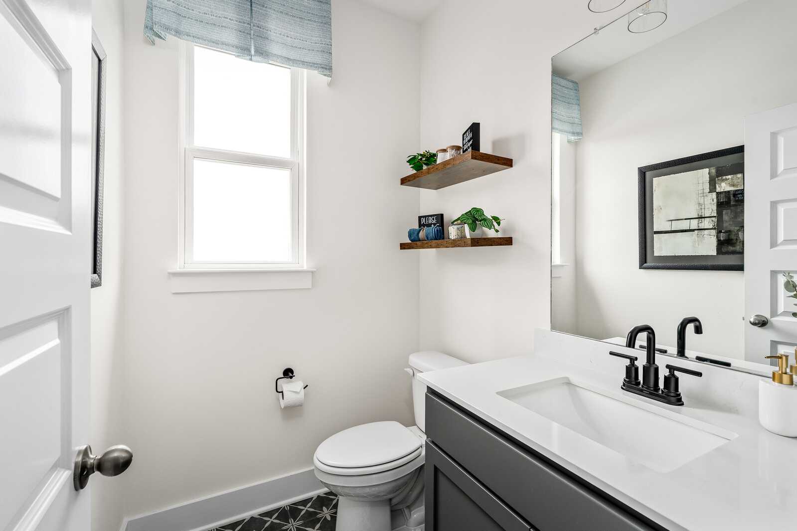 Modern bathroom at Woods Crossing in Gallatin TN by Davidson Homes with white quartz vanity, black fixtures, and plant shelves