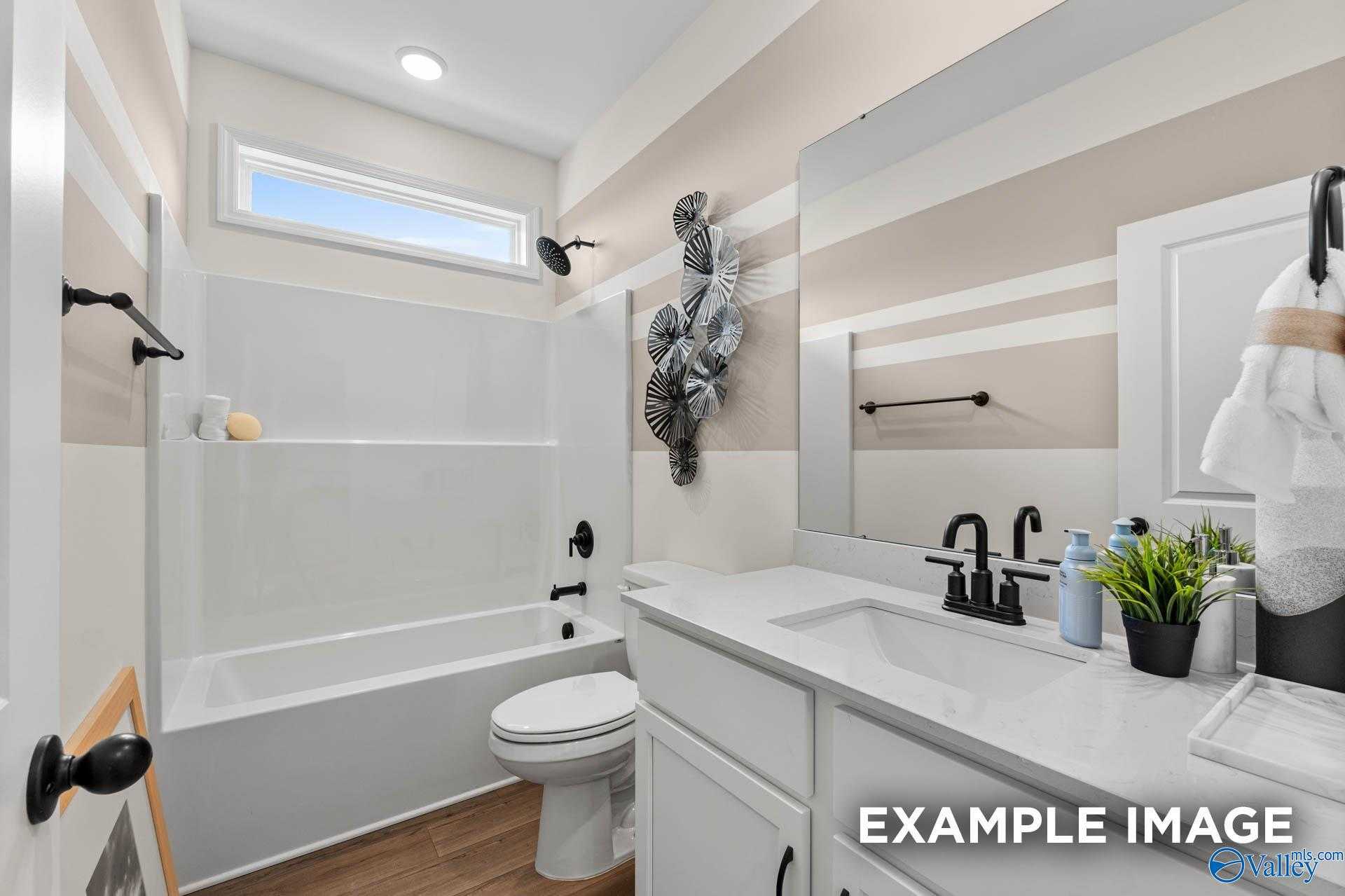 Bright guest bathroom with white tub-shower combo, vanity, and modern fixtures in Davidson Homes The Franklin, Huntsville, Alabama