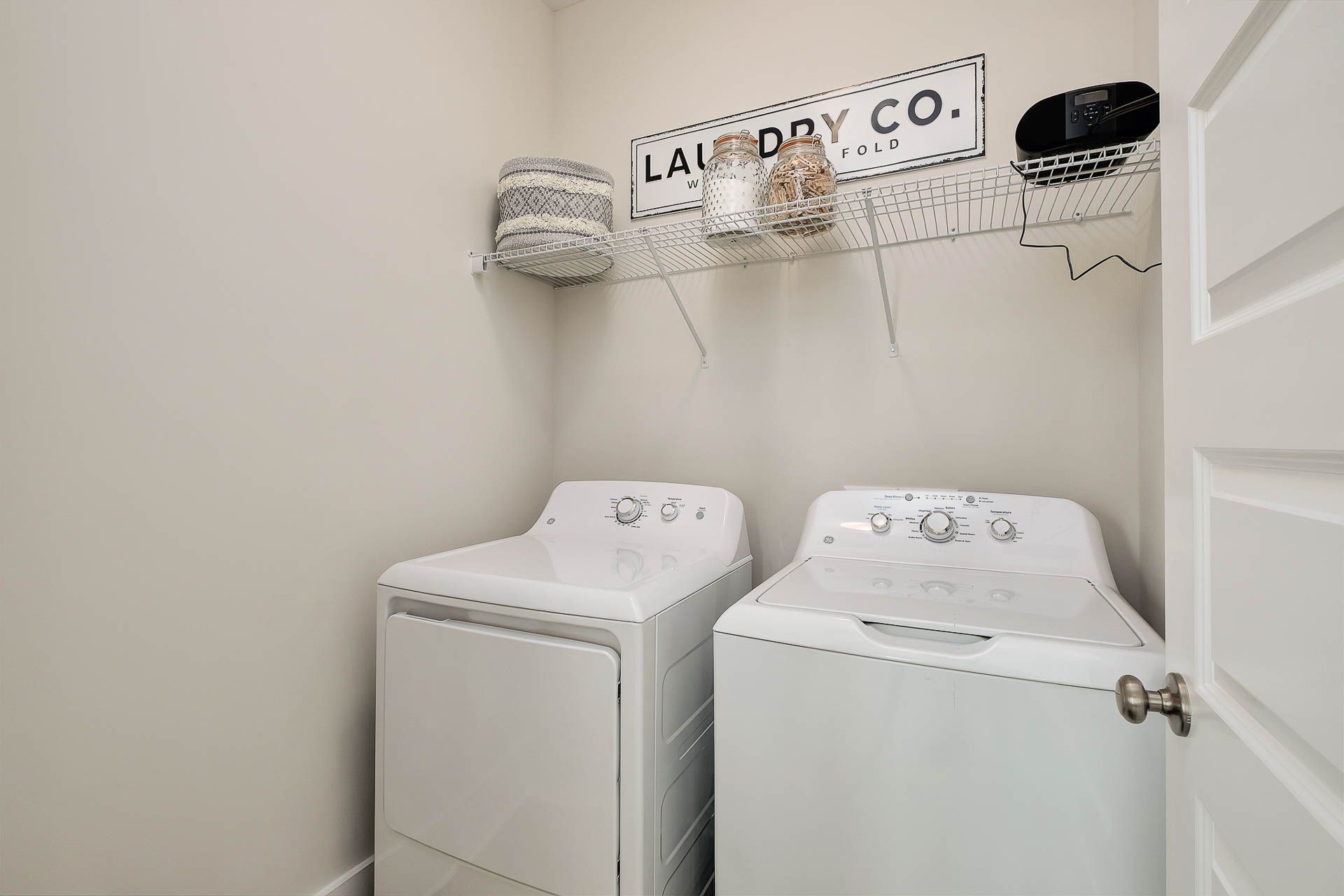 Spacious laundry room at Heritage Heights in Madison Alabama with white front-load washer dryer and vintage LAUNDRY CO. sign