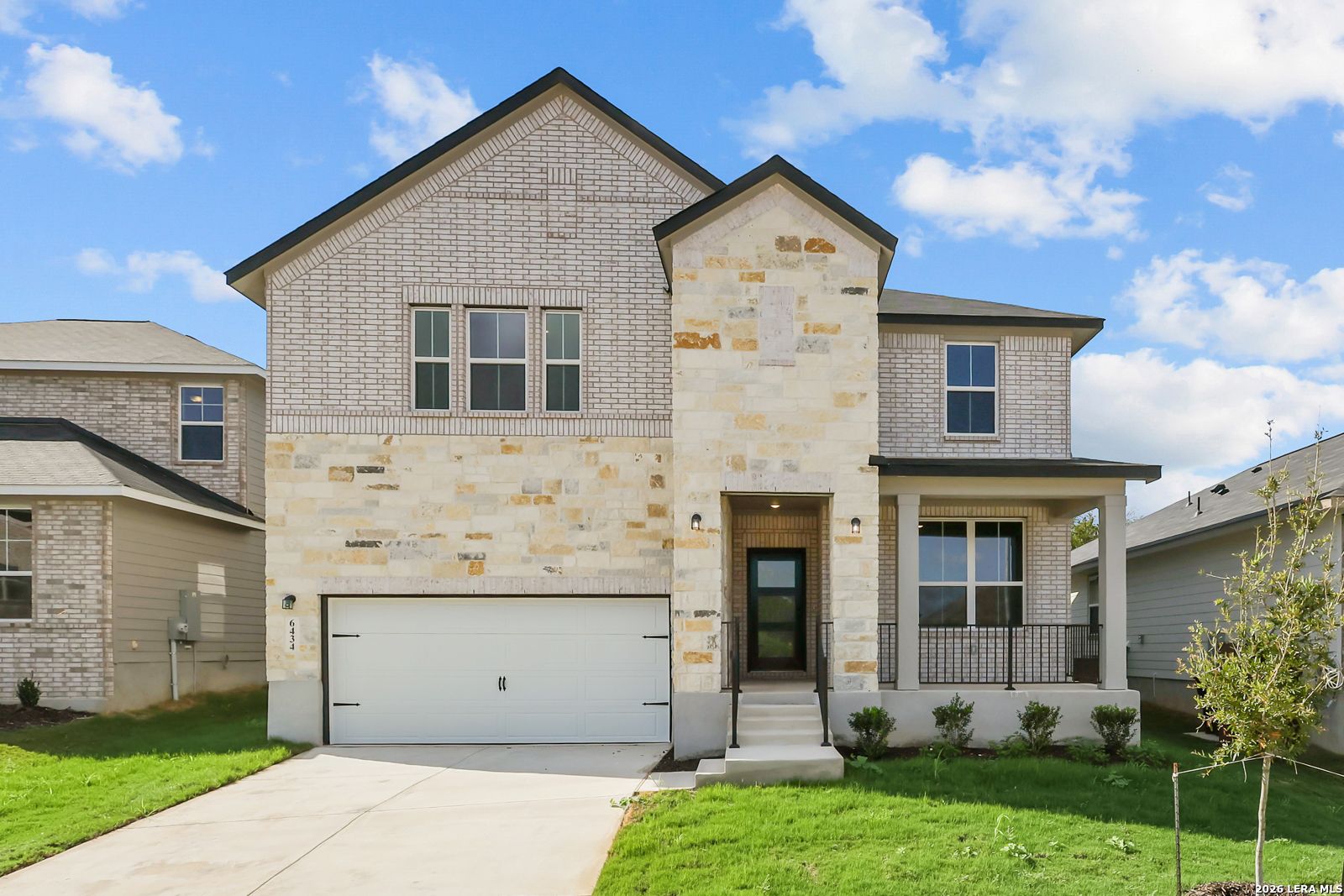 Two-story brick and stone new home with covered porch and 2-car garage at Royal Crest, San Antonio by Davidson Homes.
