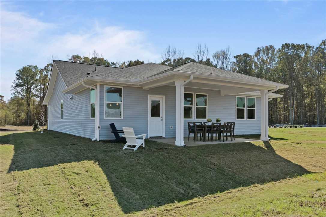 Covered back patio with white columns, glass doors, outdoor dining set on lush lawn in Davidson Homes Phoenix B, Opelika AL