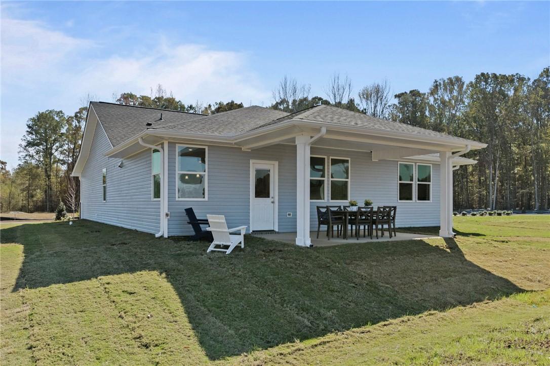 Covered rear patio with glass doors, outdoor dining set, and lush lawn in Davidson Homes The Phoenix B, Opelika, Alabama