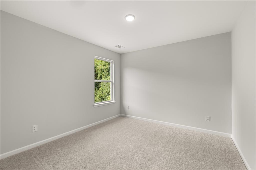 Bright and spacious secondary bedroom with neutral carpet in The Russell A floor plan at Cedar Farms in Winder, Georgia.