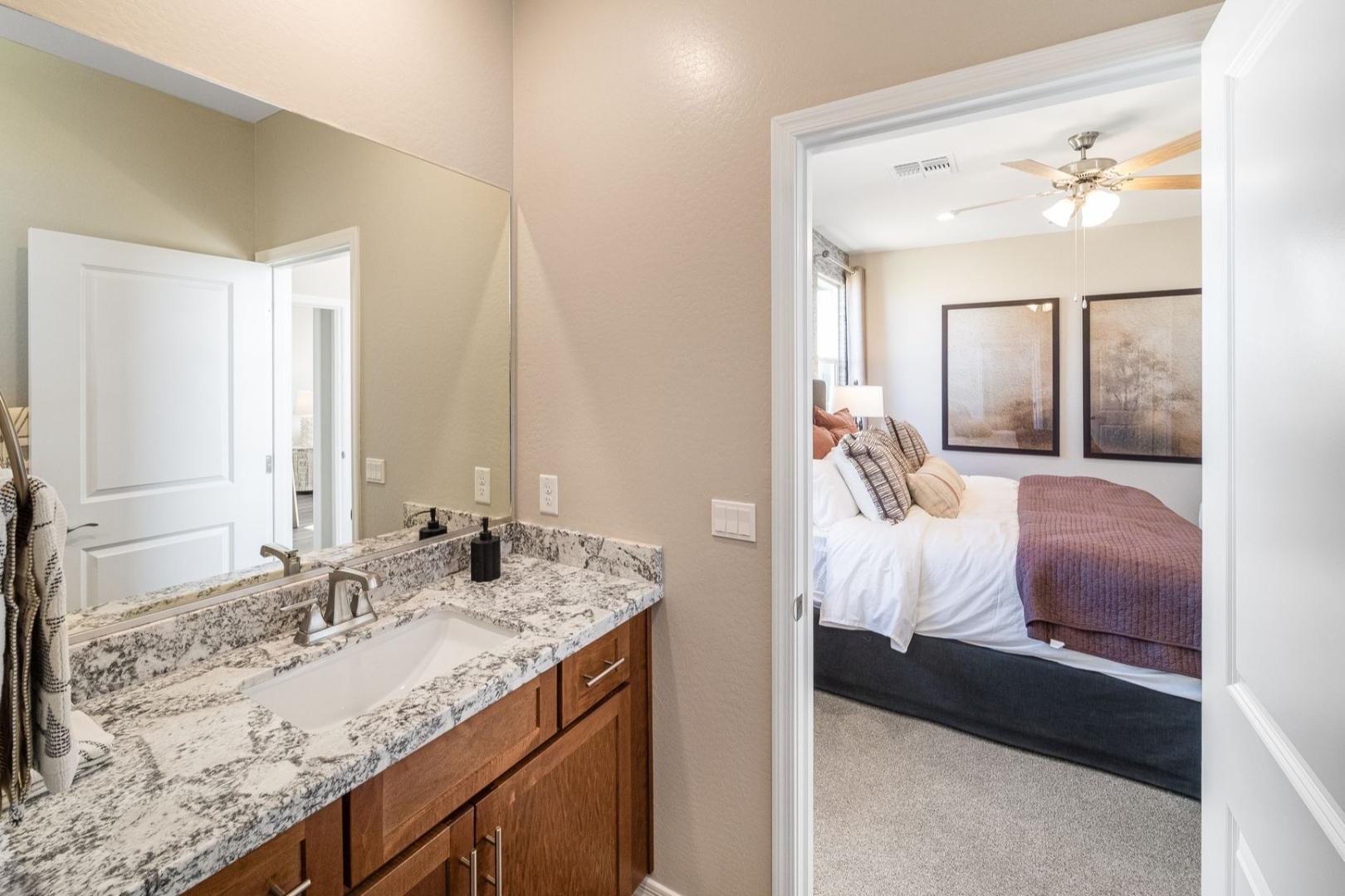 Master bathroom in The Savannah B with quartz vanity, double sink, and open view to plush master bedroom suite