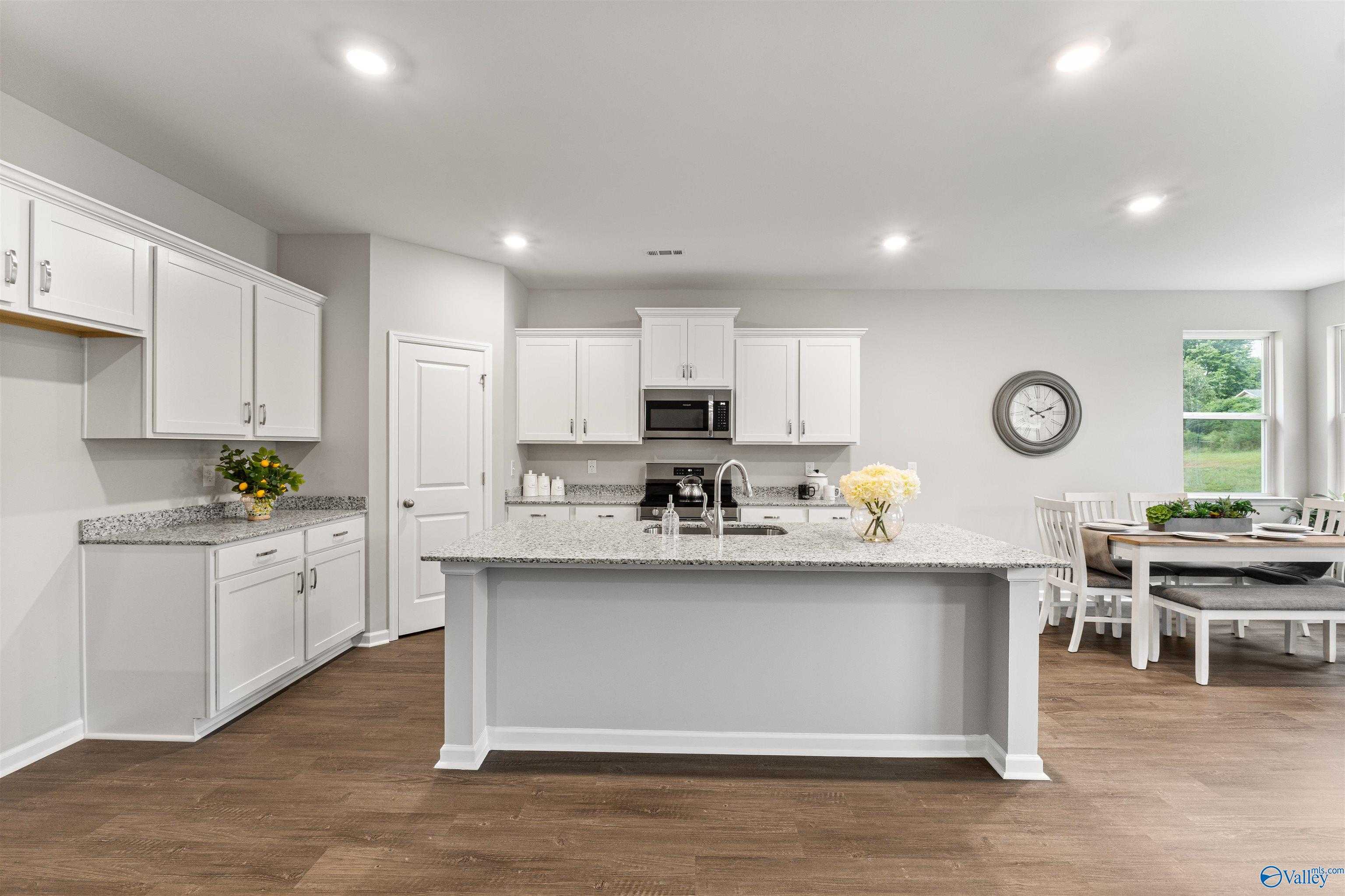 Modern white kitchen with granite island, stainless appliances, and dining nook in Davidson Homes The Phoenix, Fayetteville, TN