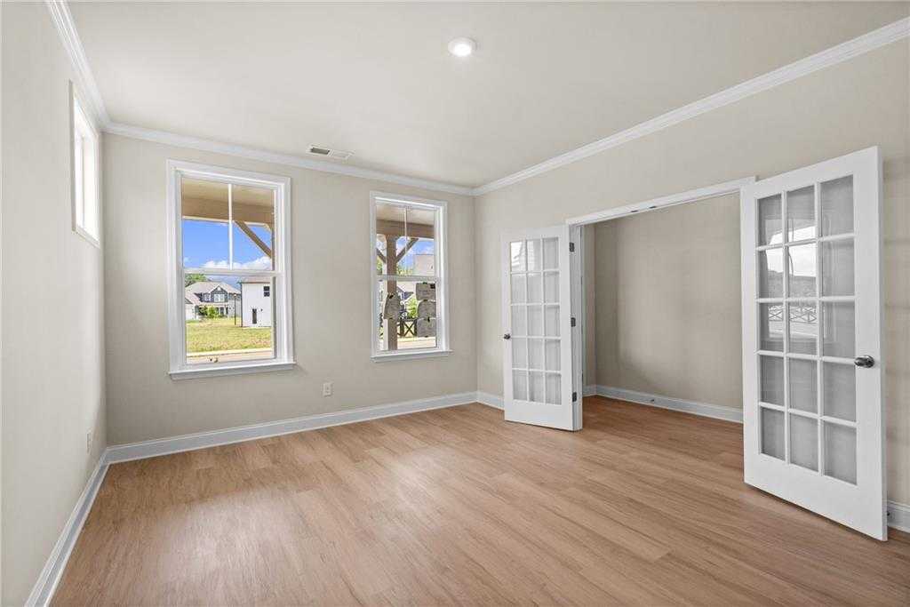 Bright airy room with large windows overlooking green yard, hardwood floors, and French doors in Davidson Homes The Hickory B at Wehunt Meadows, Hoschton