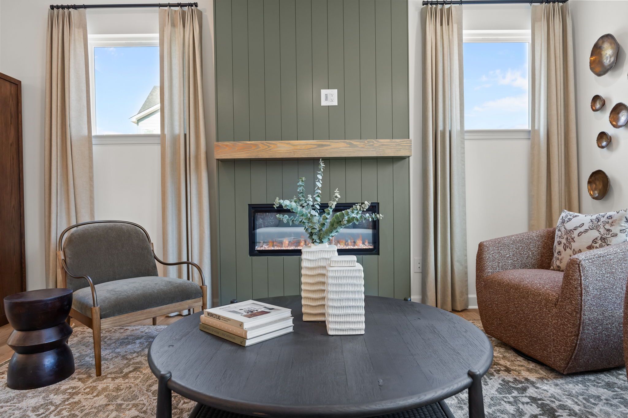 Cozy living room in Camden Park, Knightdale NC with green shiplap wall, gas fireplace, armchairs and round coffee table