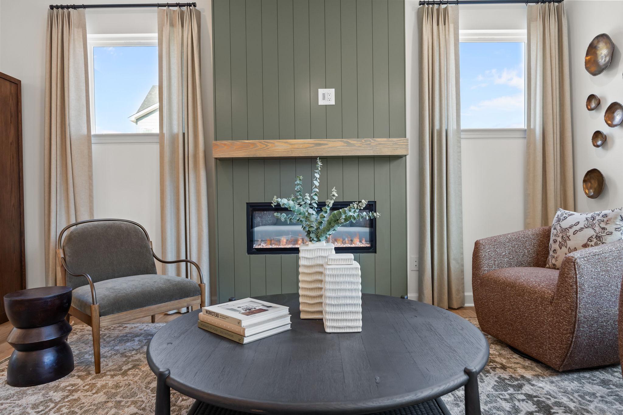 Cozy living room in Camden Park, Knightdale NC with green shiplap wall, gas fireplace, armchairs and round coffee table