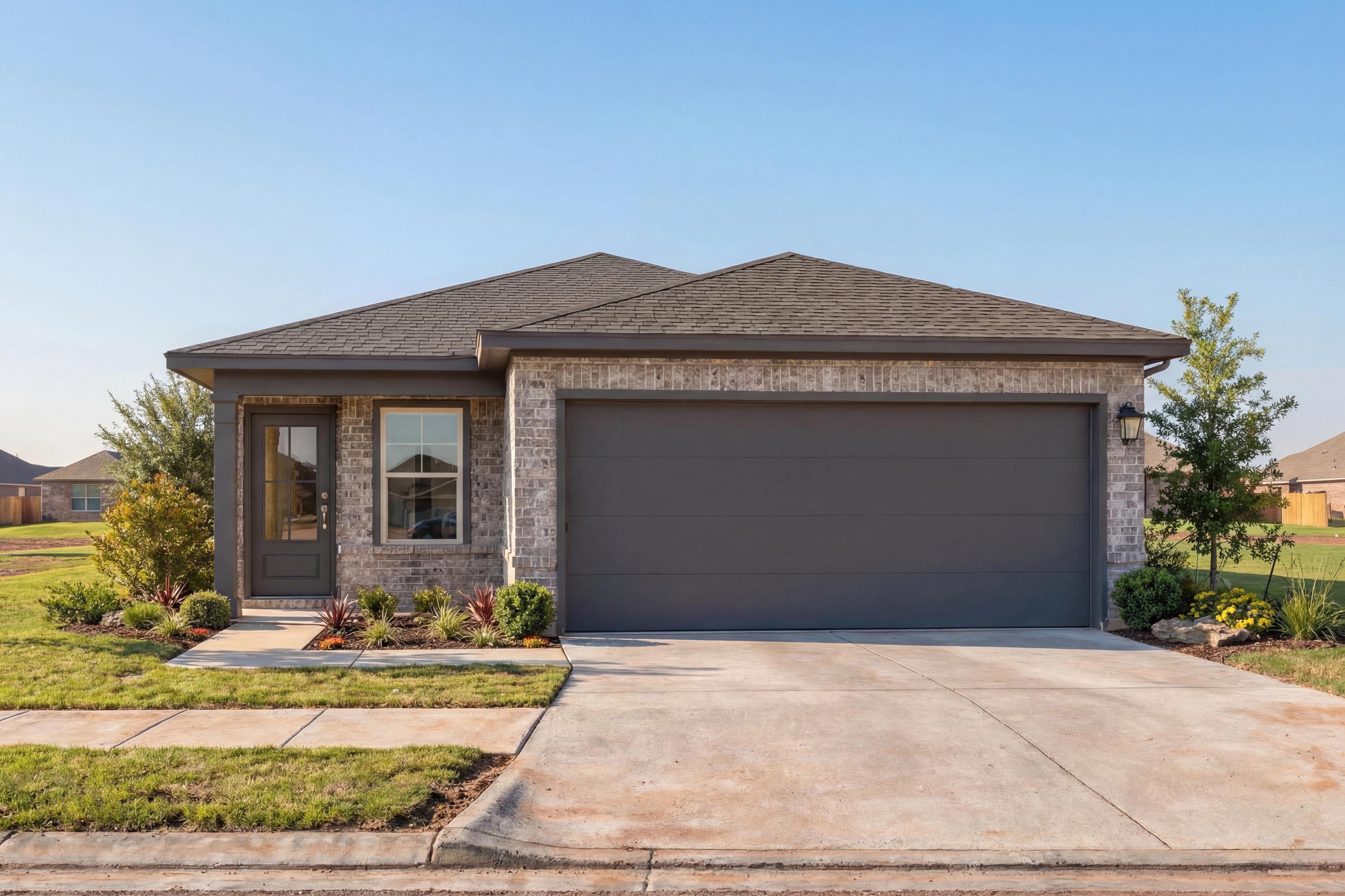 Front elevation of The Colorado F single-story home with brick accents, gray garage, and landscaped yard in Magnolia, Texas