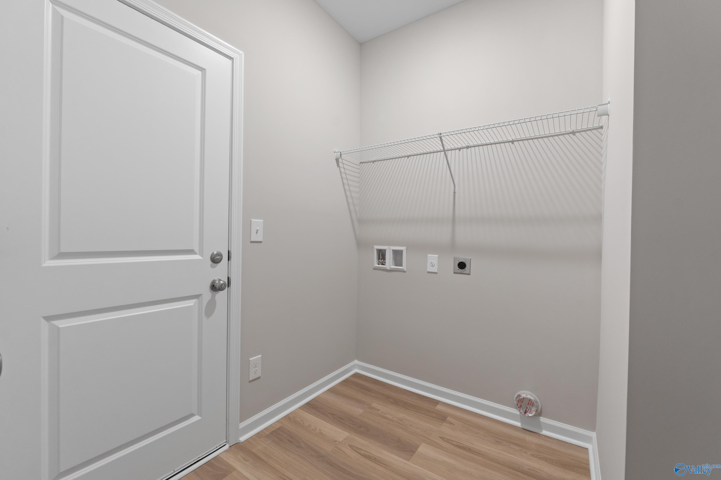 Functional laundry room with white shelving, washer/dryer hookups, and gray walls in Davidson Homes The Augusta, Madison, AL