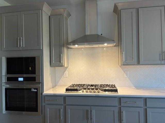 Contemporary kitchen with gray shaker cabinets, quartz counters, stainless steel range, and subway tile backsplash in Davidson Homes Marion A, Winder, GA