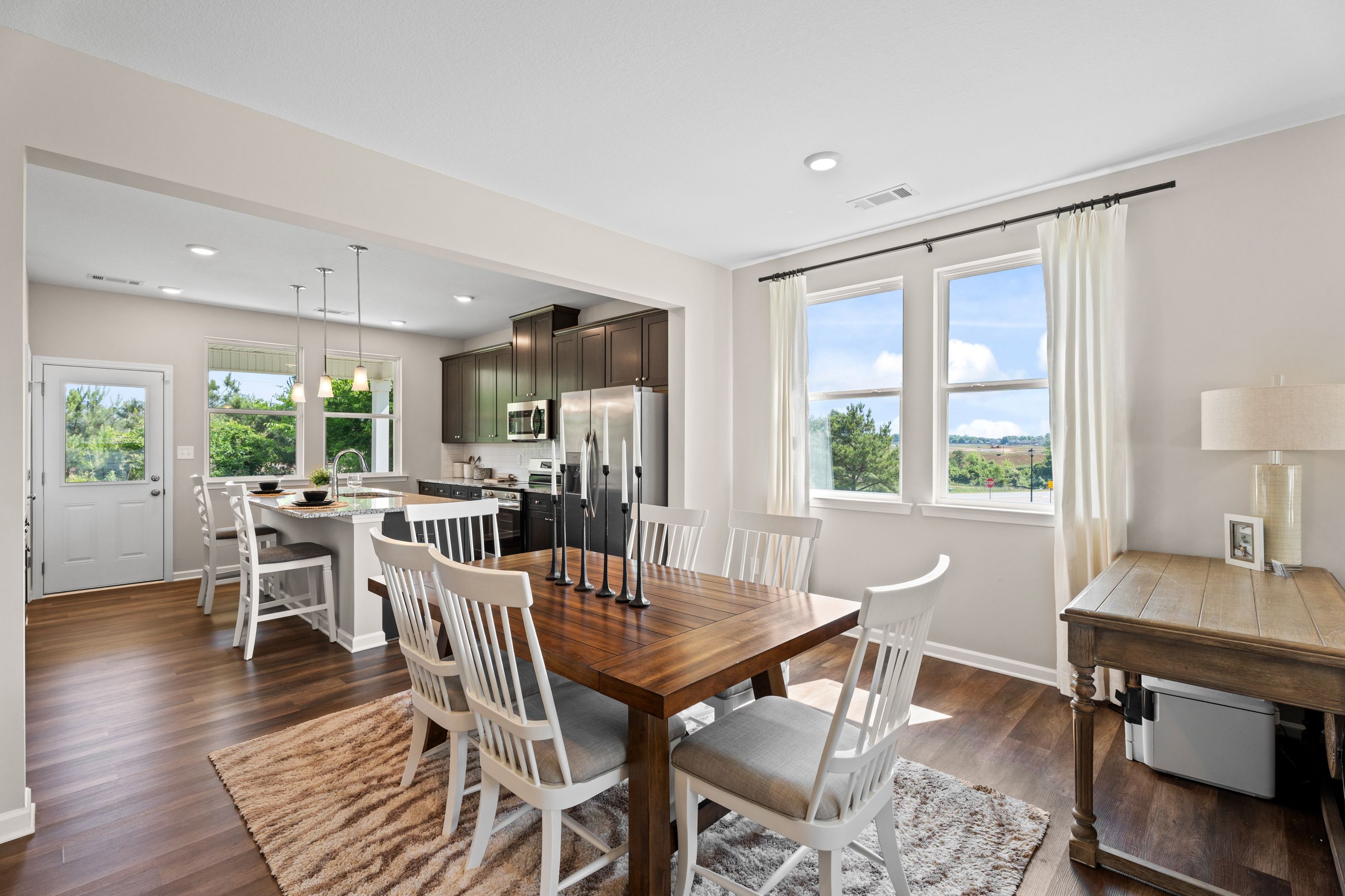 Spacious open-concept dining area at Ivy Glen in Perry Georgia by Evermore Homes with wooden table white chairs hardwood floors and living room view