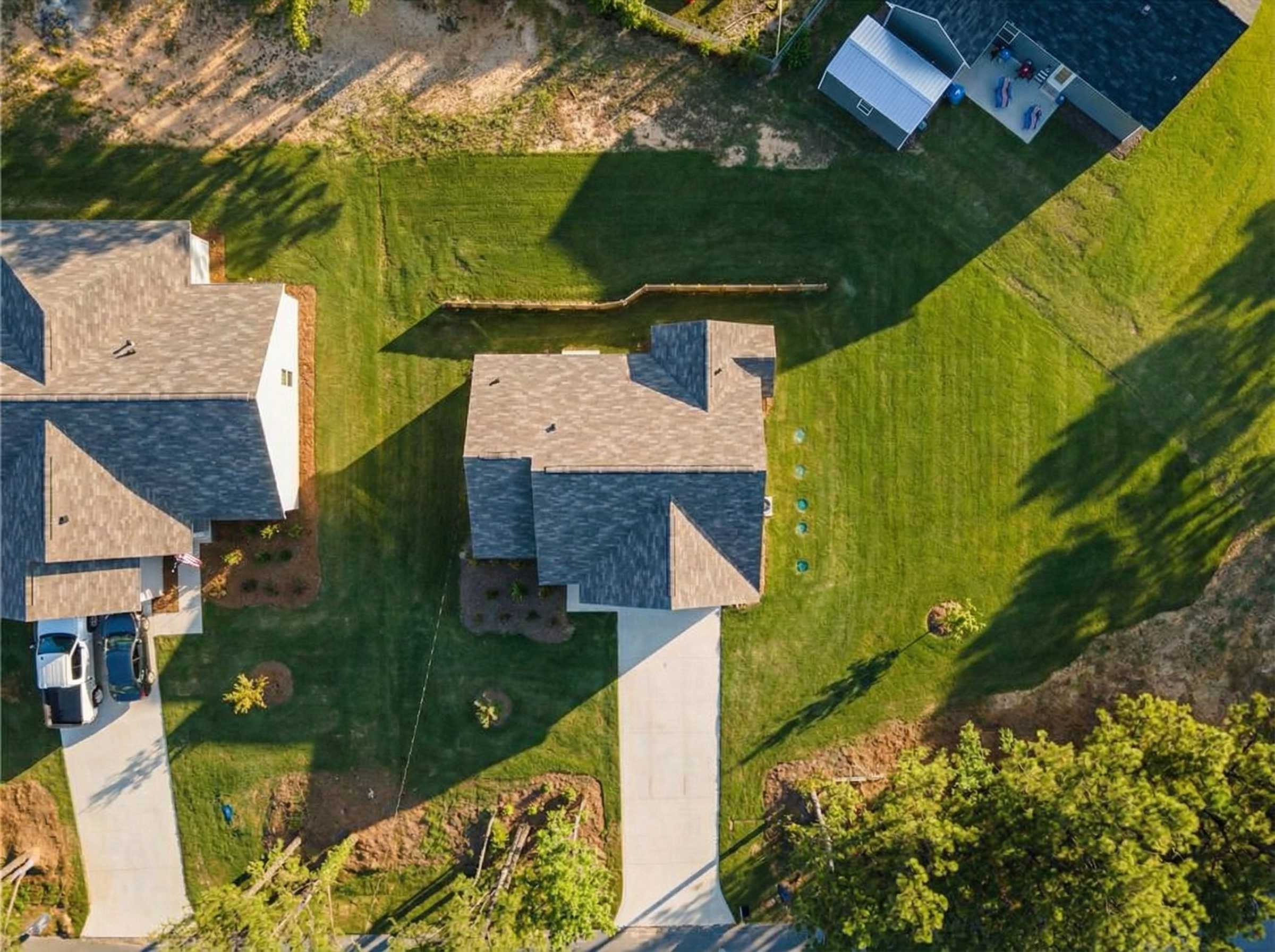 Aerial view of The Washington 3-bedroom single-story home by Evermore Homes, gray shingle roof, driveway, landscaped yard in Heatherbrook, Phenix City, Alabama