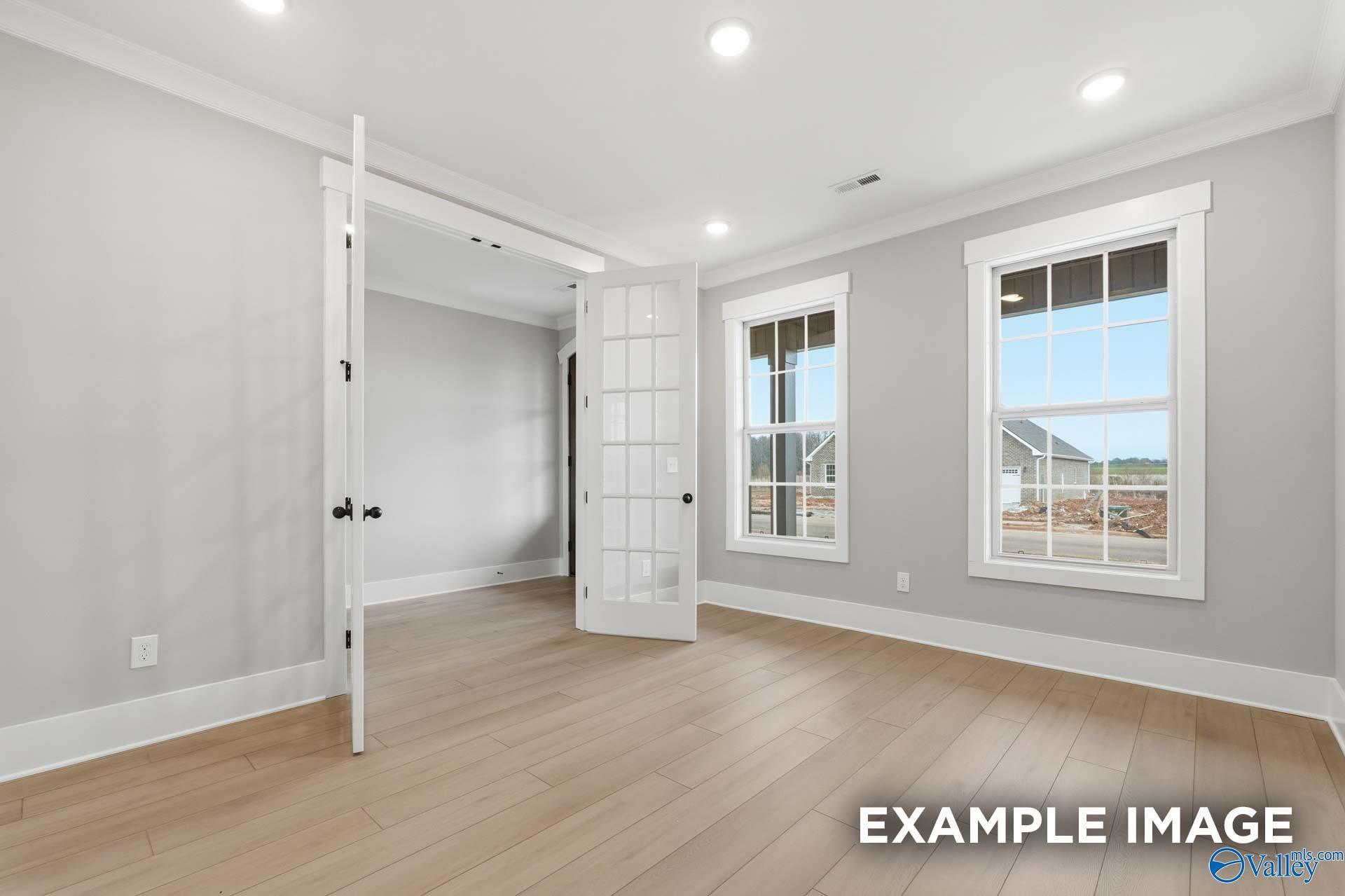 Bright interior with open glass-paneled French doors, hardwood floors, and large windows in Davidson Homes The Emory, Decatur AL