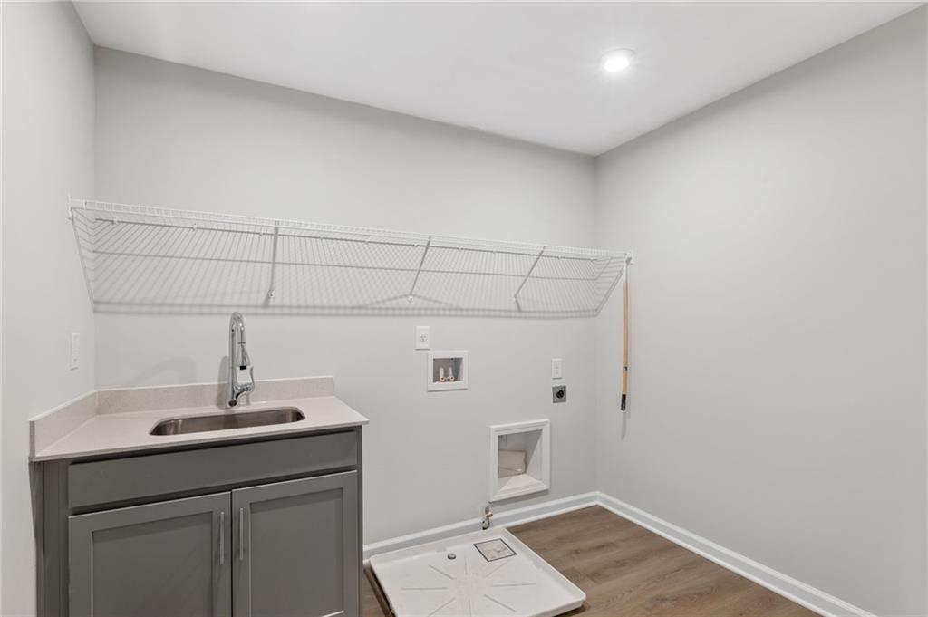 Modern laundry room featuring gray utility sink, wire shelving, and washer-dryer hookups in Davidson Homes The Marion A, Winder, GA