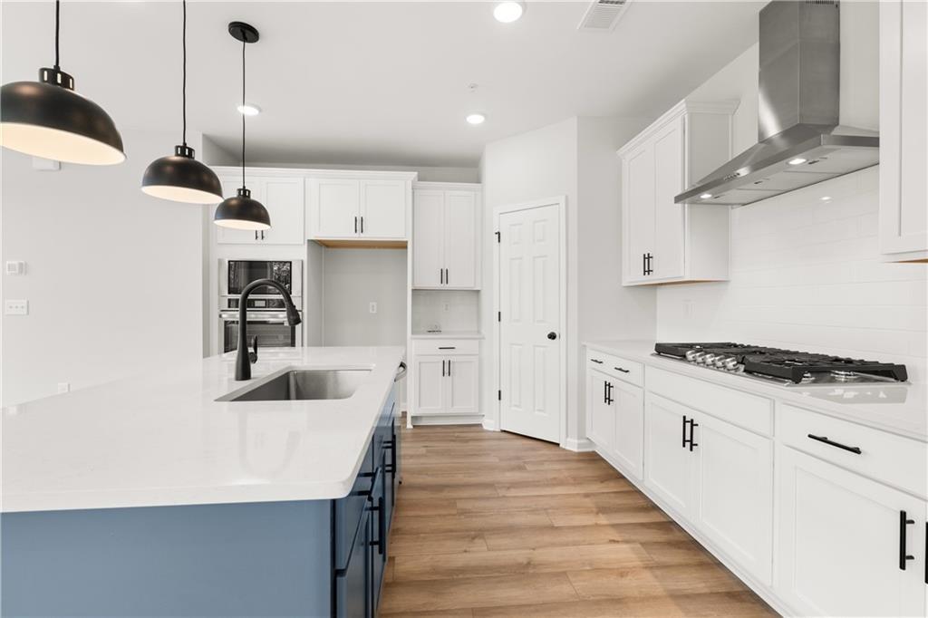 Modern kitchen with white cabinets, blue island, and stainless appliances in The Durham D floor plan, Hemingway, Cumming.