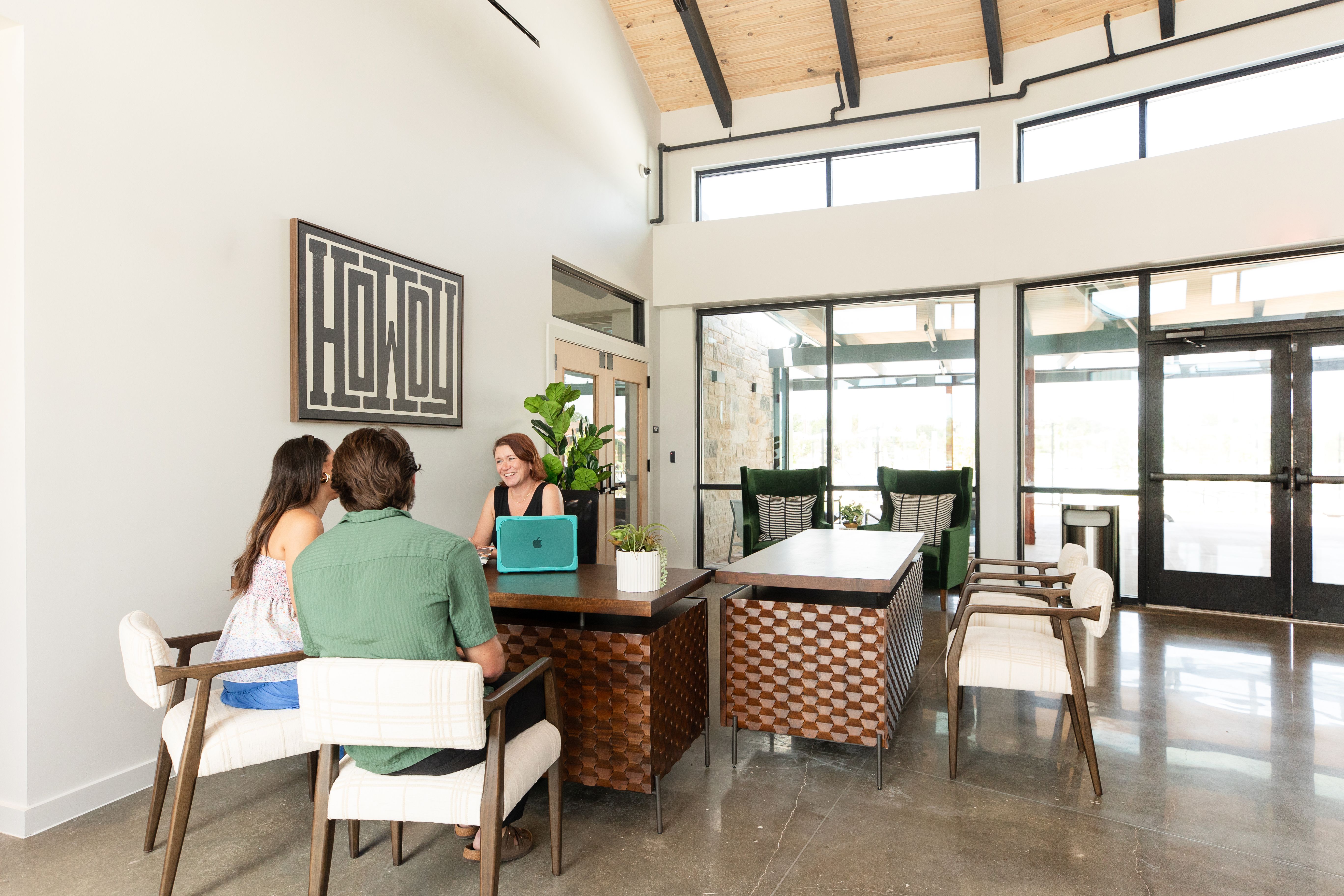 Welcoming reception desk at Emberly in Beasley, Texas by Davidson Homes with carved wood furniture, plants, and large windows